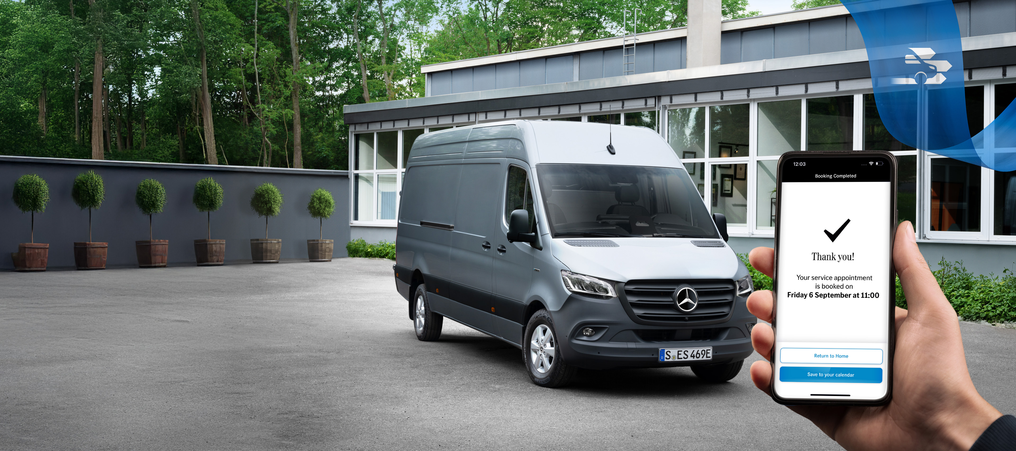 Mercedes Benz | Conveniencia | Reserva de cita online Un furgón Mercedes-Benz Sprinter gris delante de un edificio de oficinas con una mano sosteniendo un smartphone en primer plano.