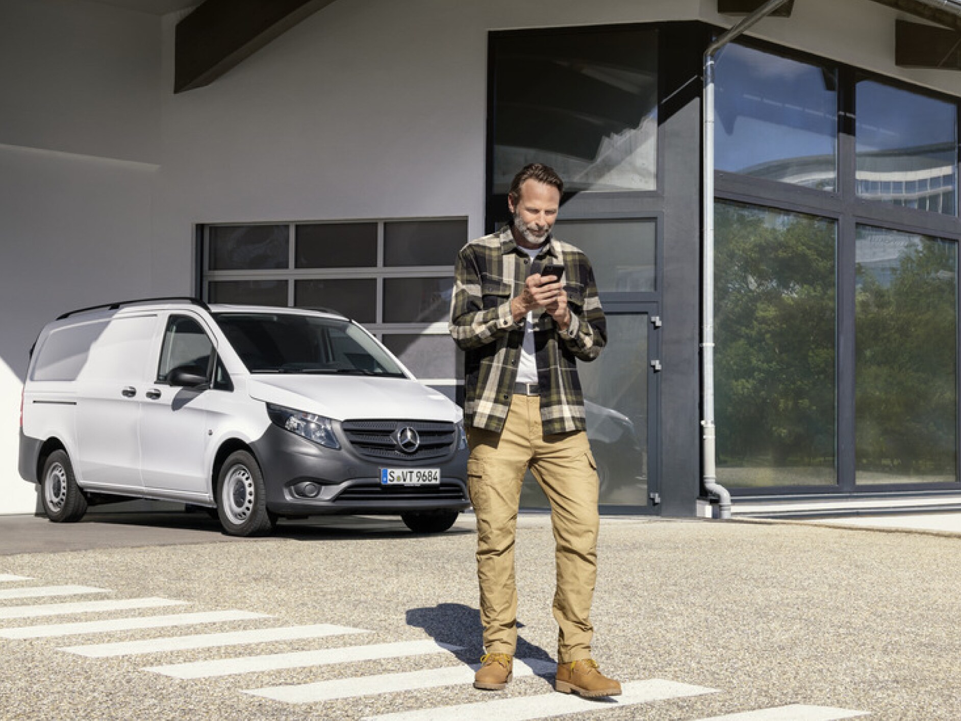 Una persona con un smartphone delante de una Mercedes-Benz Vito.