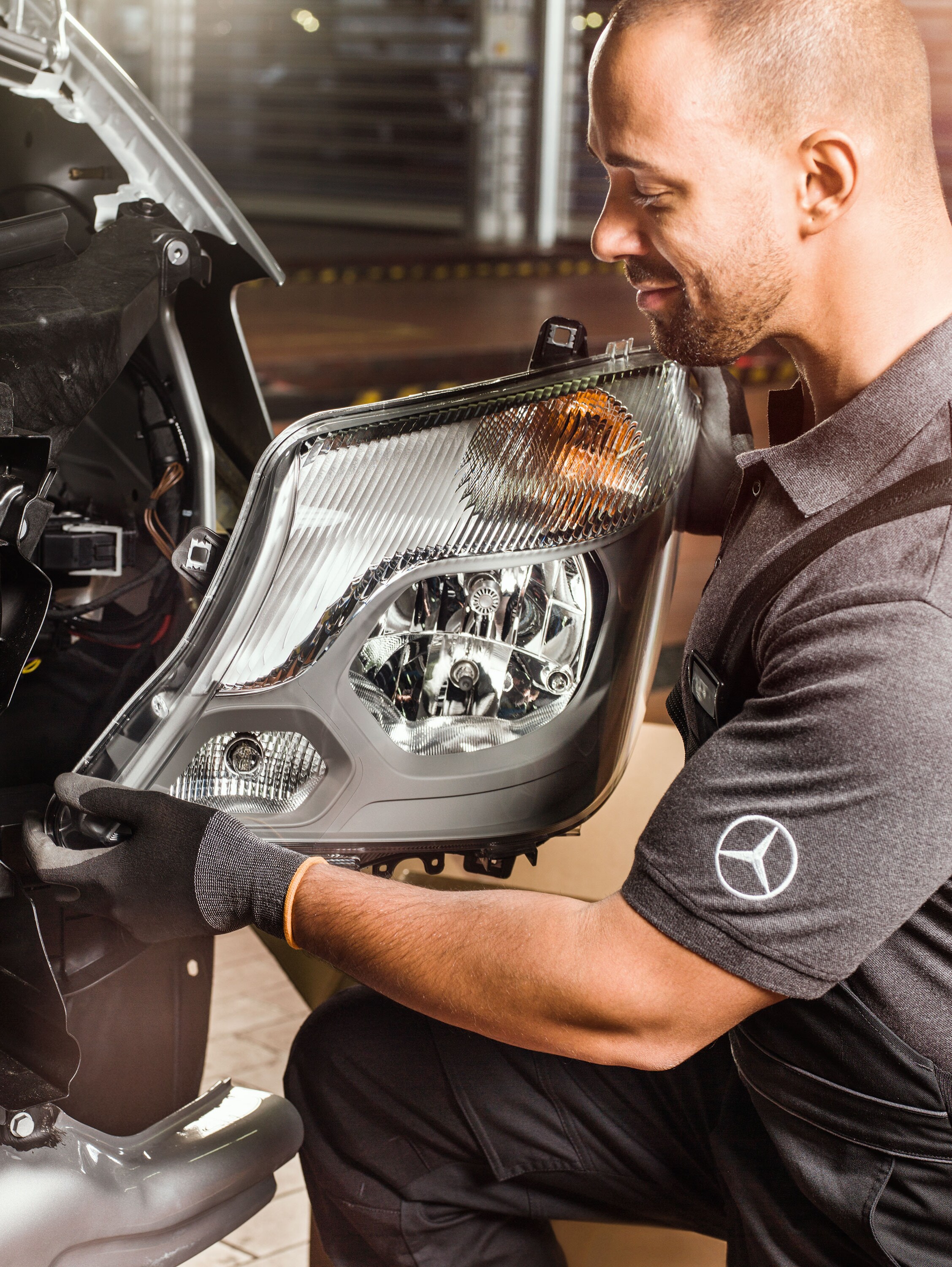 Mecánico comprobando recambios originales Mercedes-Benz delante de un motor Sprinter abierto, cotejando el catálogo de piezas de repuesto Mercedes.