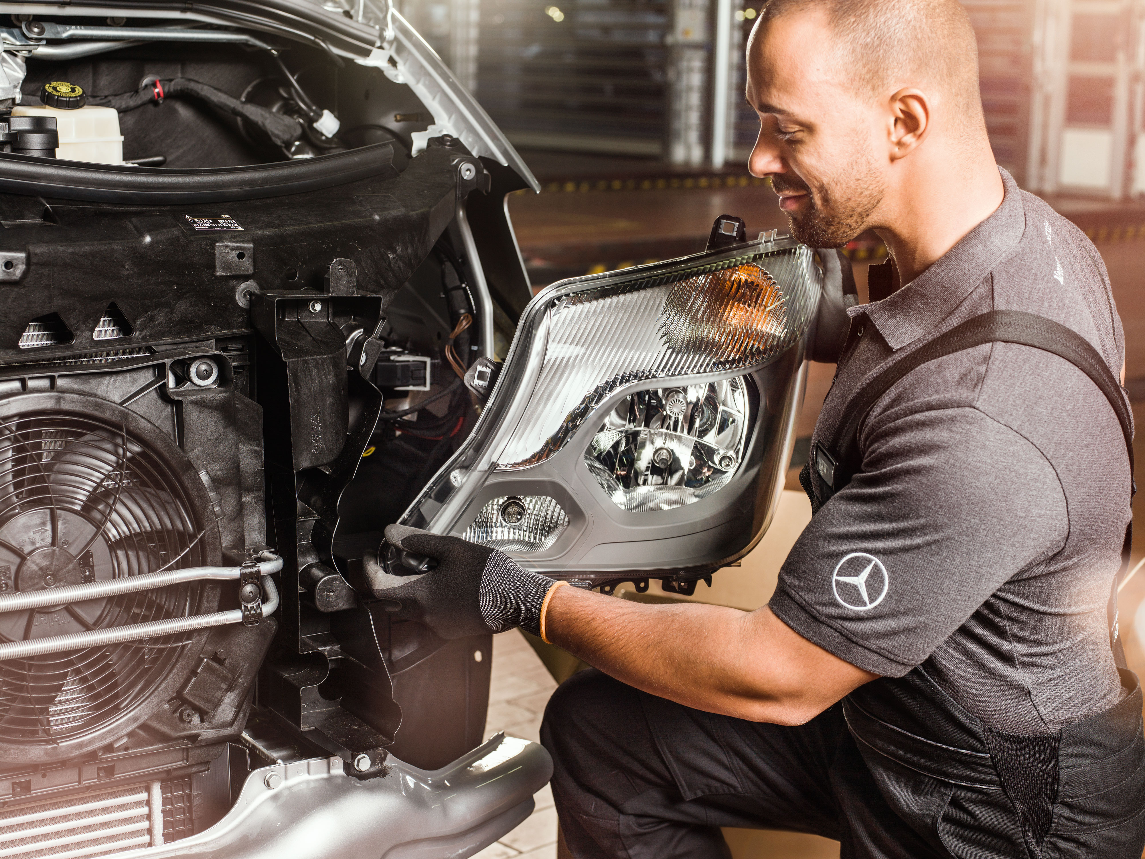 Mercedes-Benz | Recambios originales de calidad para furgones Mecánico comprobando recambios originales Mercedes-Benz delante de un motor Sprinter abierto, cotejando el catálogo de piezas de repuesto Mercedes.
