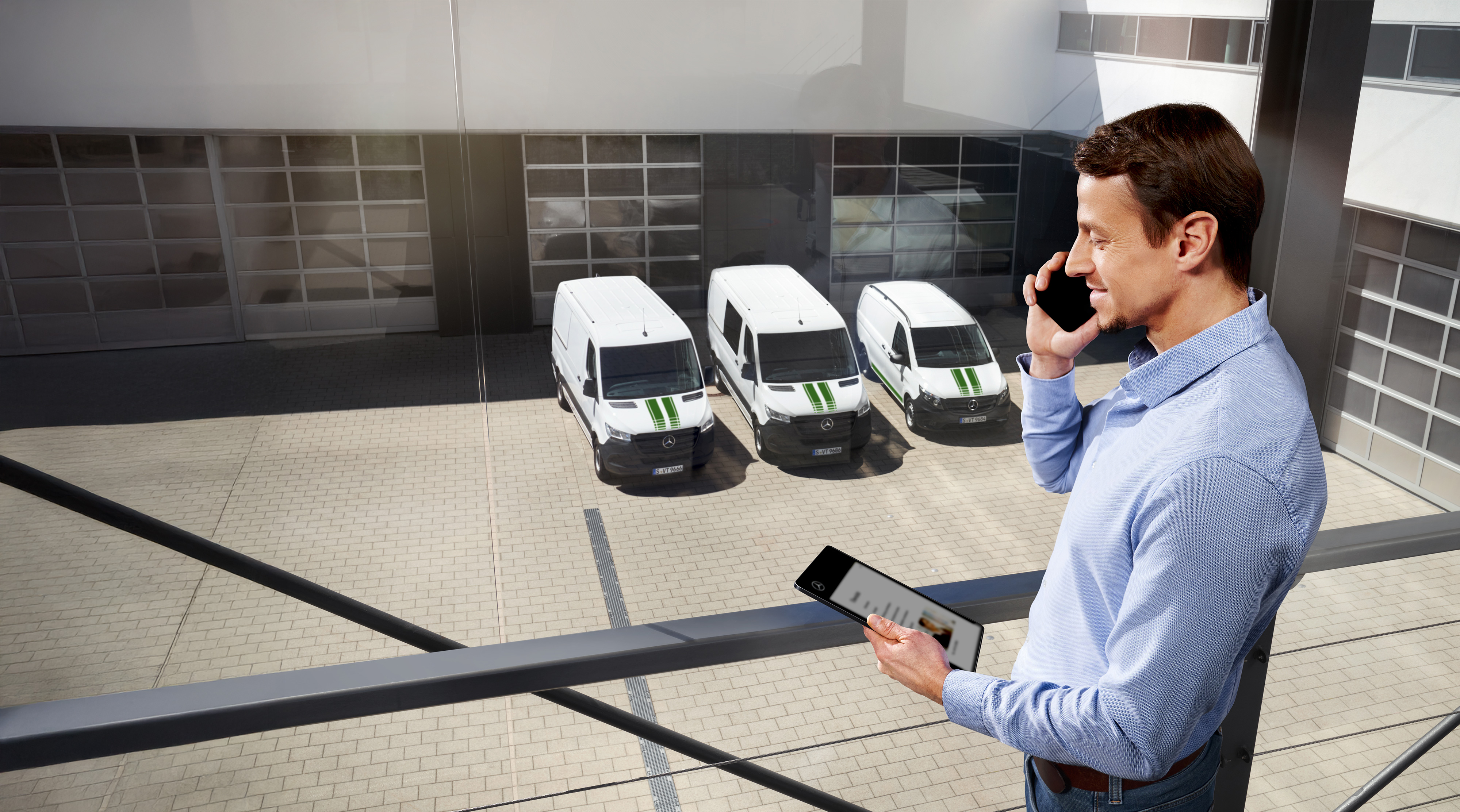 Mercedes-Benz | Garantía de Calidad para Furgones Hombre hablando por teléfono con tablet delante de tres furgones Mercedes-Benz, tema: ¿cuál es la duración de la garantía del fabricante en Mercedes-Benz?