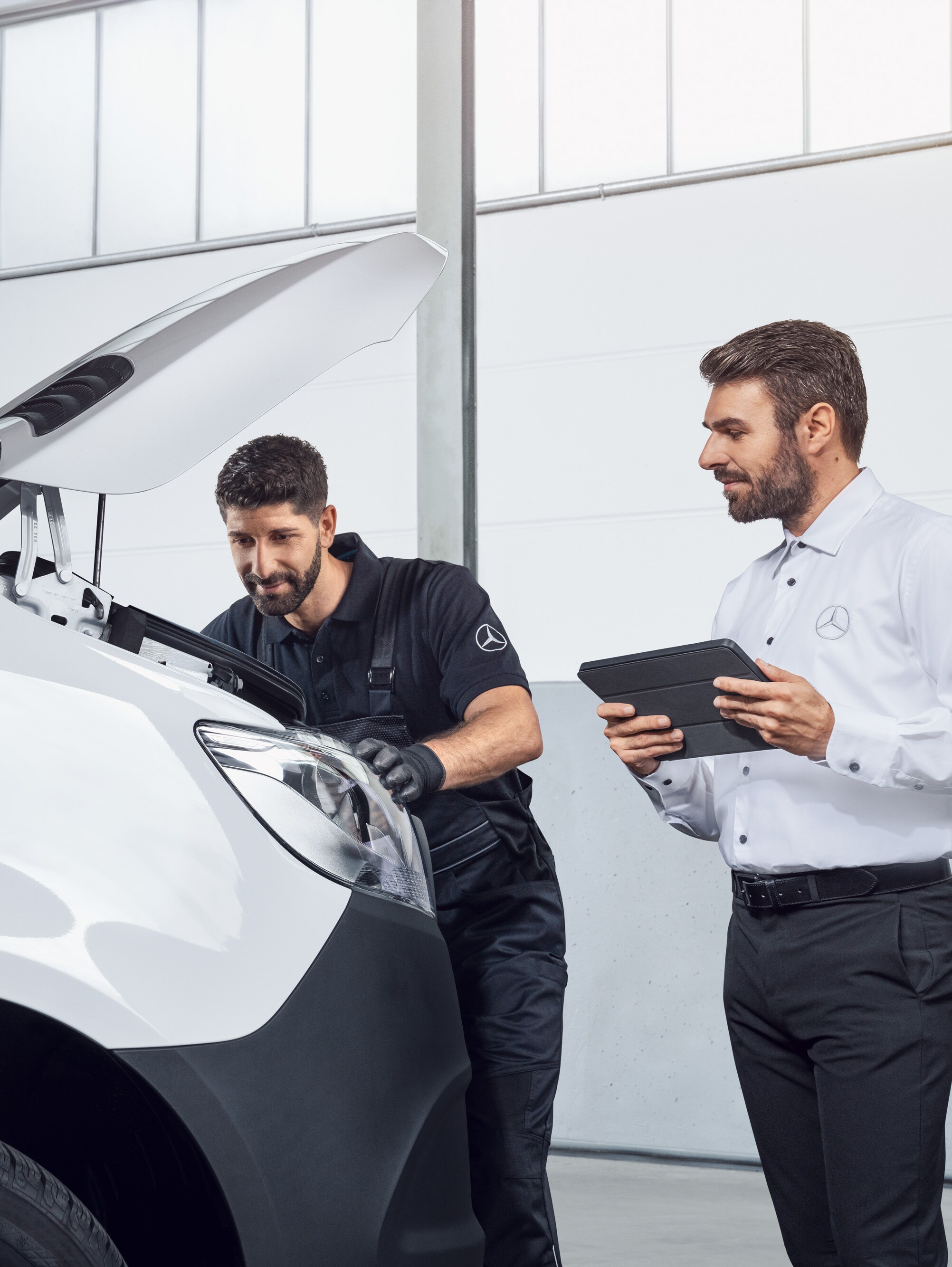 Dos hombres probando un Mercedes Sprinter con tablet y capó abierto, tema: repuestos de Sprinter Mercedes-Benz.