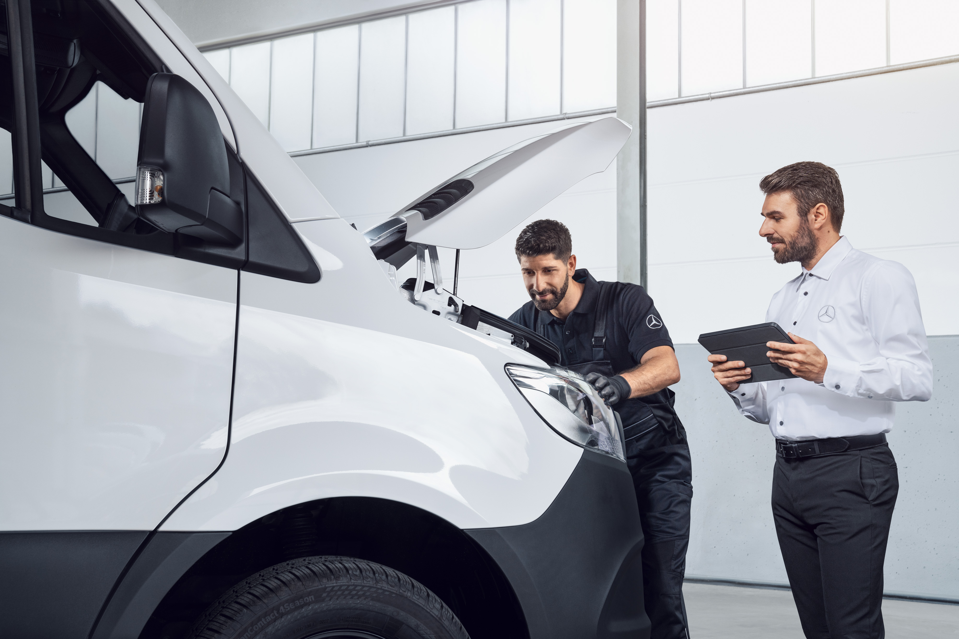 Mercedes-Benz | Recambios originales de calidad para furgones Dos hombres testeando un Mercedes Sprinter con tablet y capó abierto, tema: repuestos de Sprinter Mercedes-Benz.