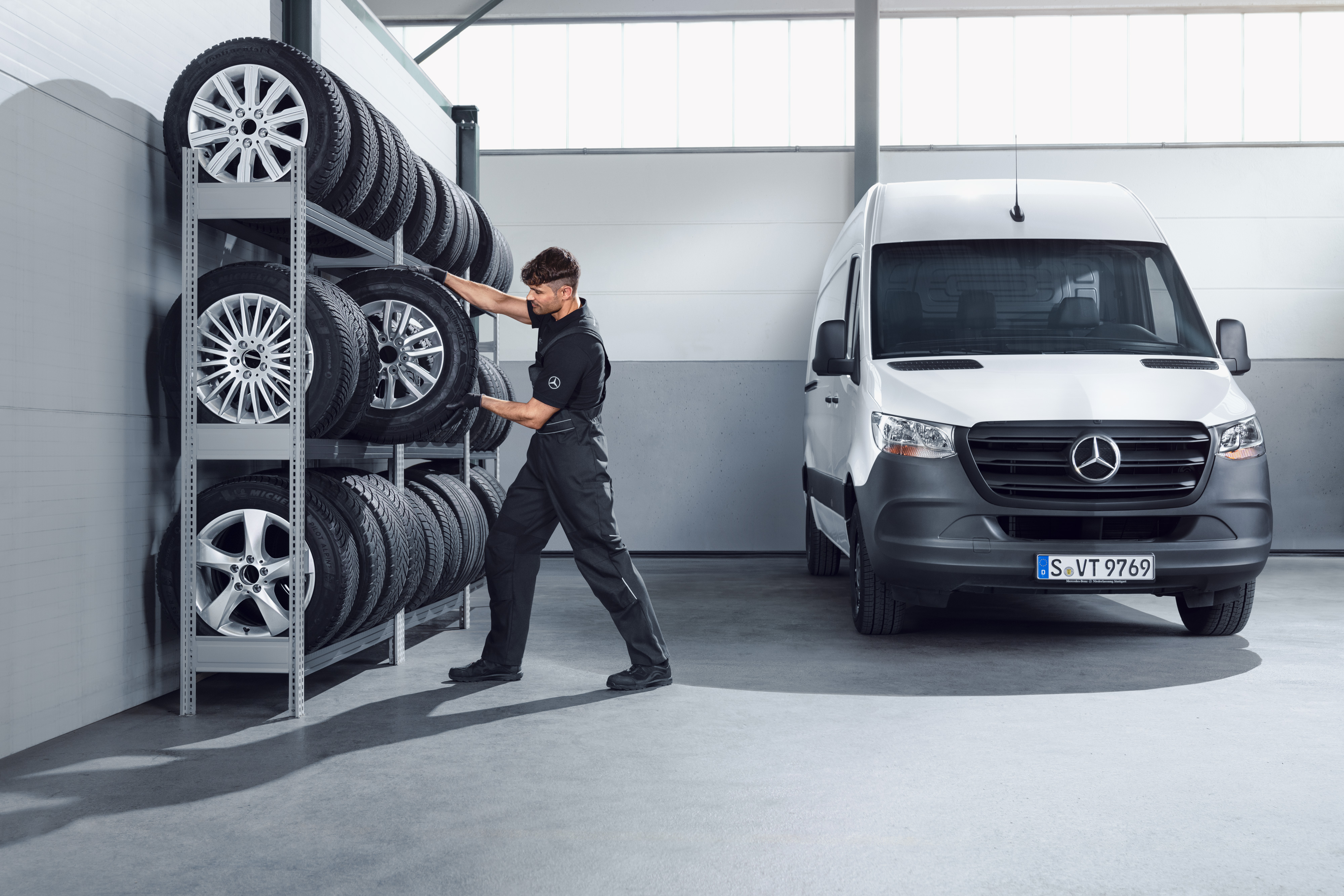 Mercedes-Benz | Recambios originales de calidad para furgones Mecánico eligiendo, de la estantería del taller, ruedas Mercedes-Benz de invierno completas para un Sprinter blanco.