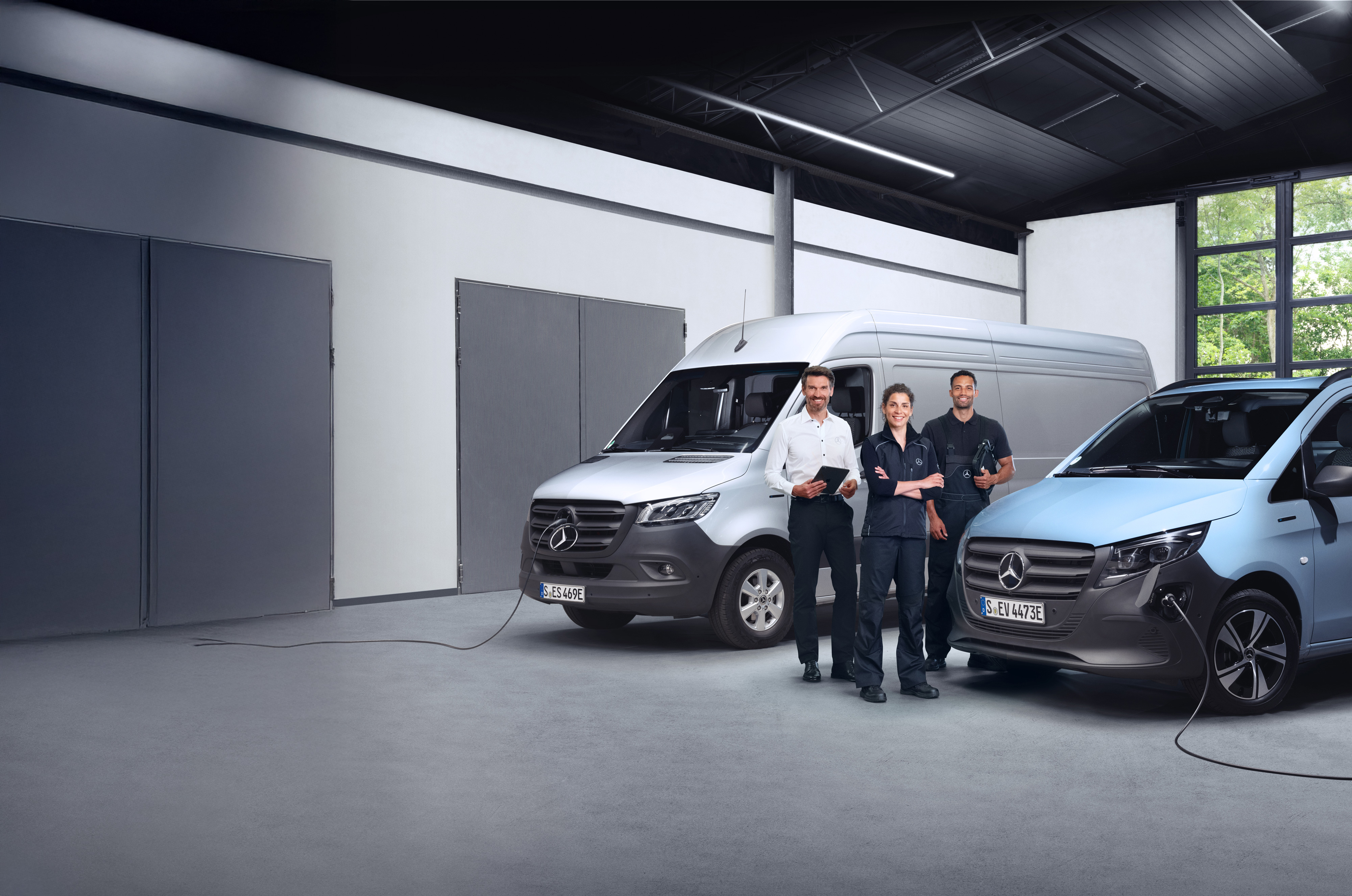 Mercedes-Benz | Vista general de calidad de los furgones Tres empleados delante de furgonetas Mercedes-Benz, simbolizando calidad.
