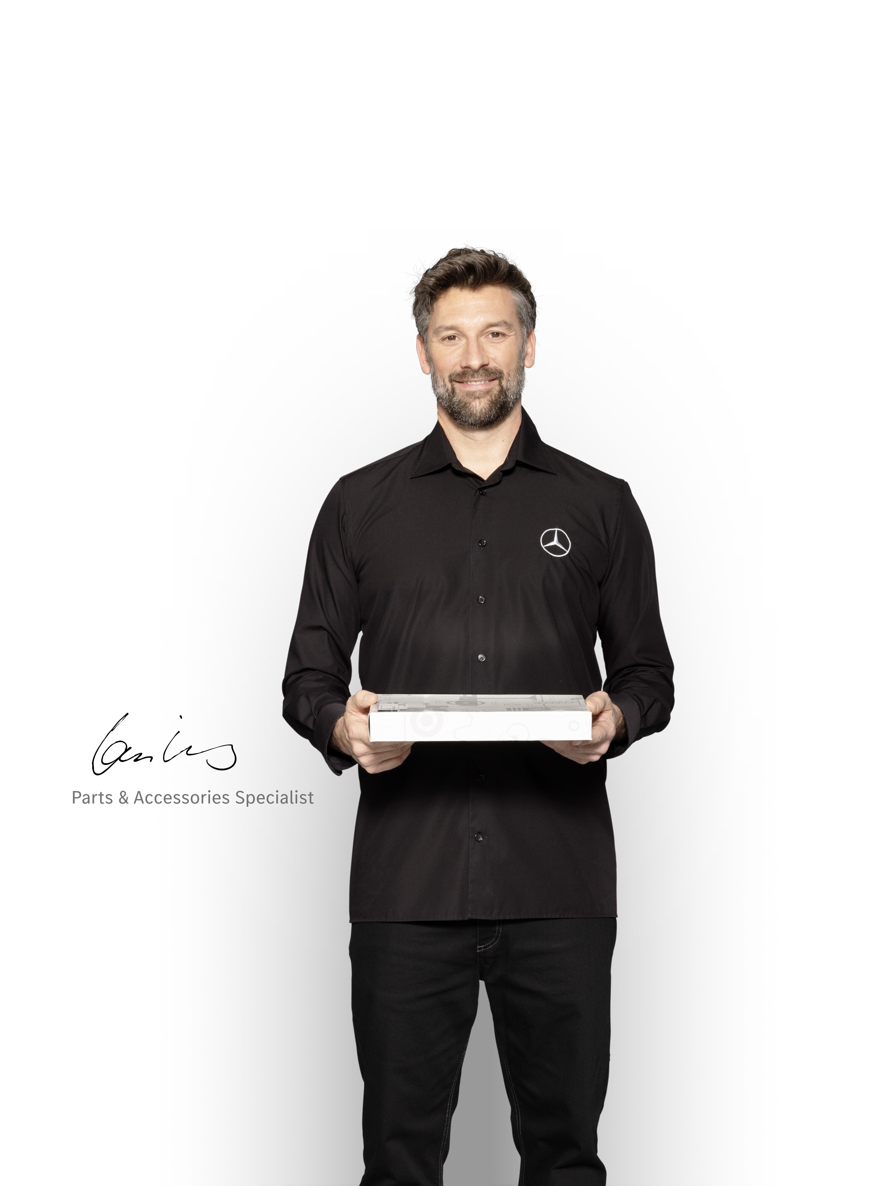 Técnico interno de Mercedes-Benz con una caja en las manos para mostrar piezas originales Mercedes-Benz.