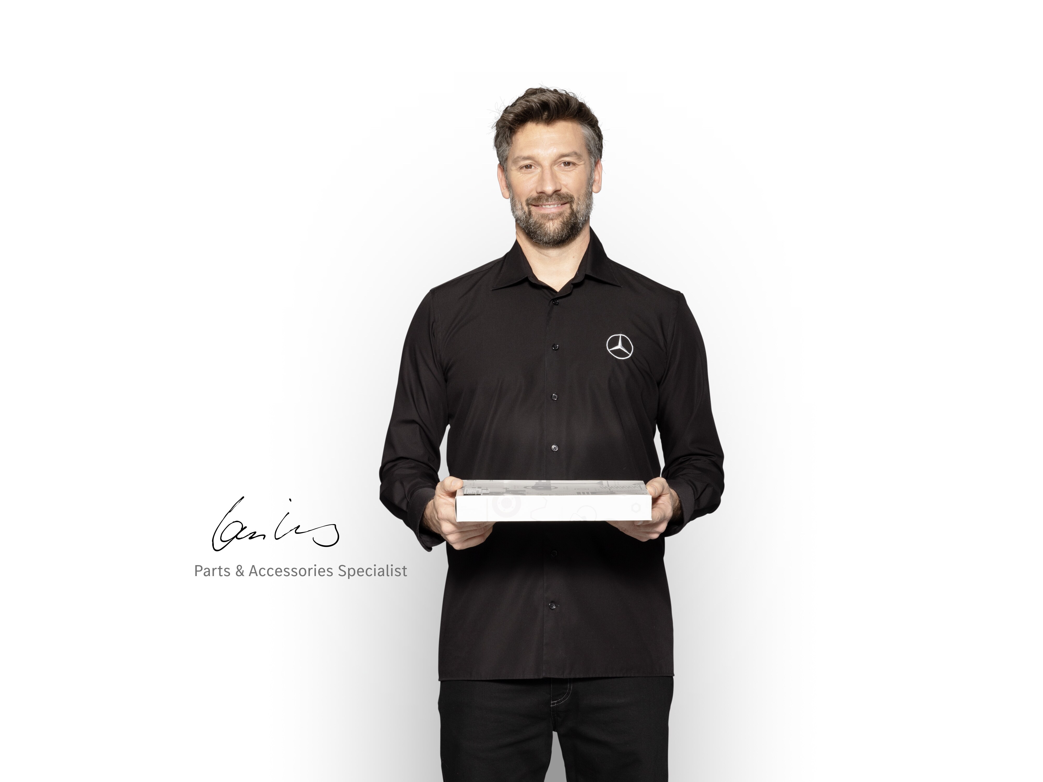 Técnico interno de Mercedes-Benz con una caja en las manos para mostrar recambios originales Mercedes-Benz.