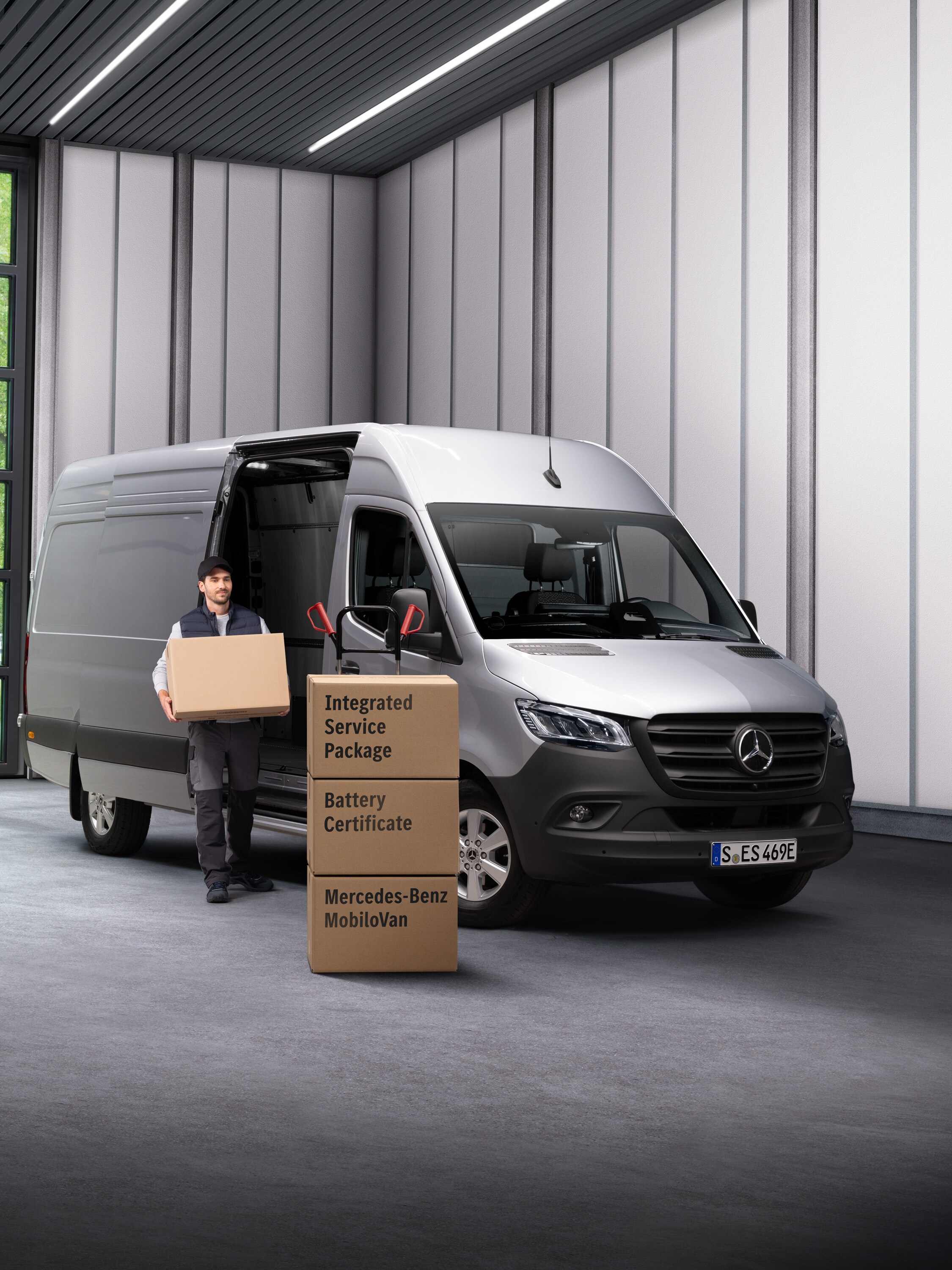 Un empleado del servicio eléctrico de Mercedes-Benz sacando cajas de un vehículo de transporte