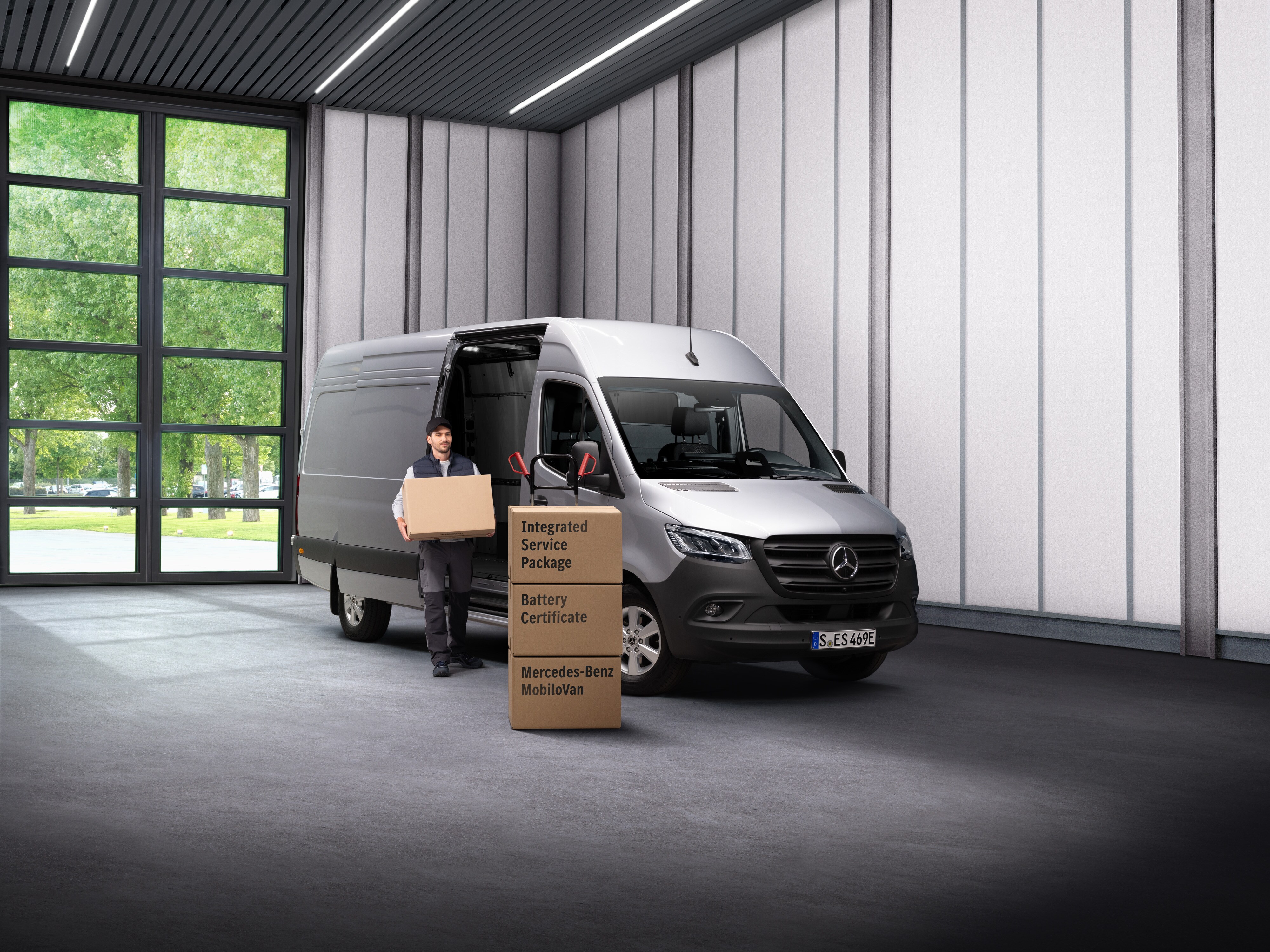 Un empleado del servicio eléctrico de Mercedes-Benz sacando cajas de un vehículo de transporte