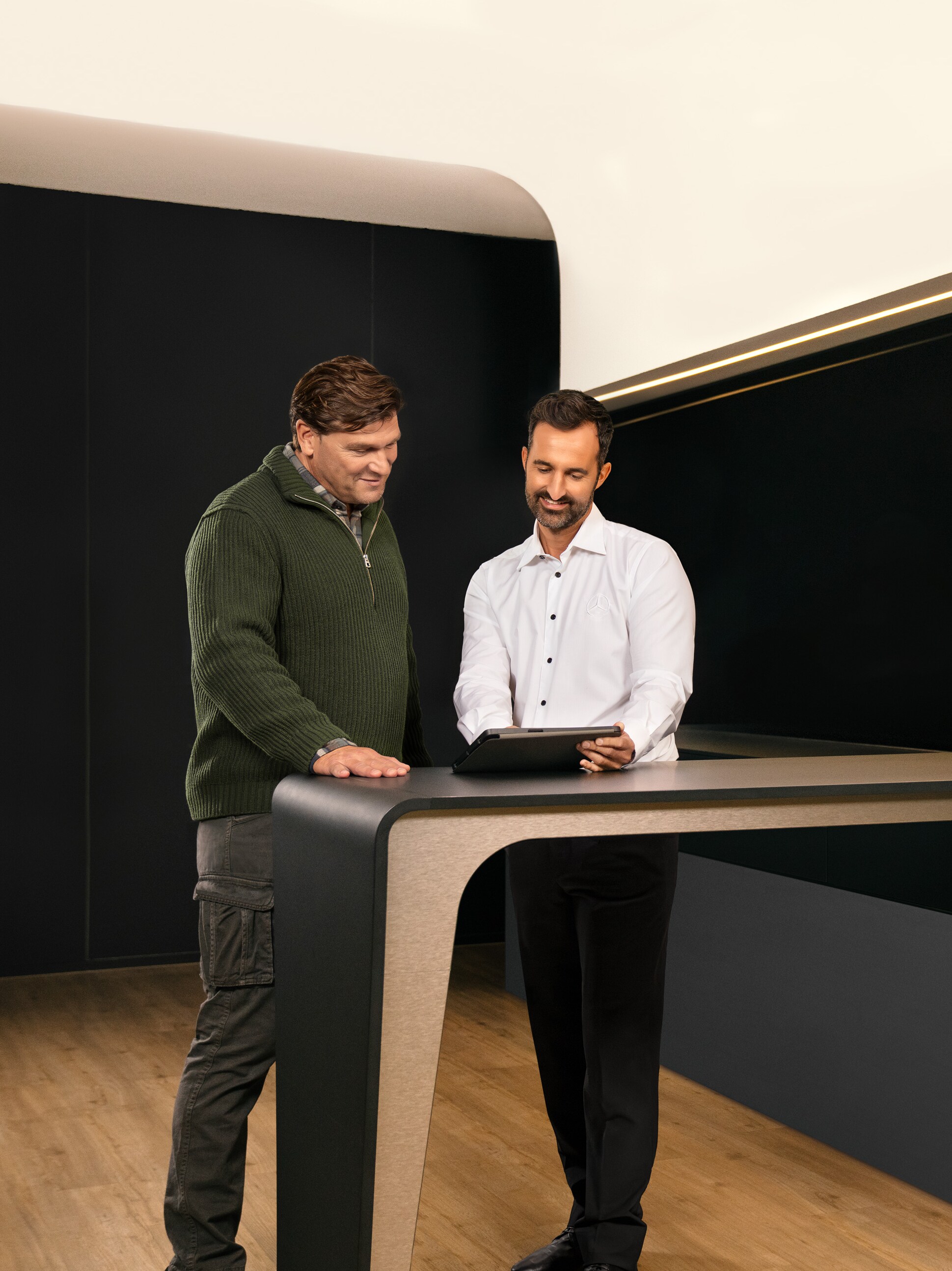 Dos hombres con una tablet, conversando sobre el servicio para vehículos industriales de Mercedes-Benz .
