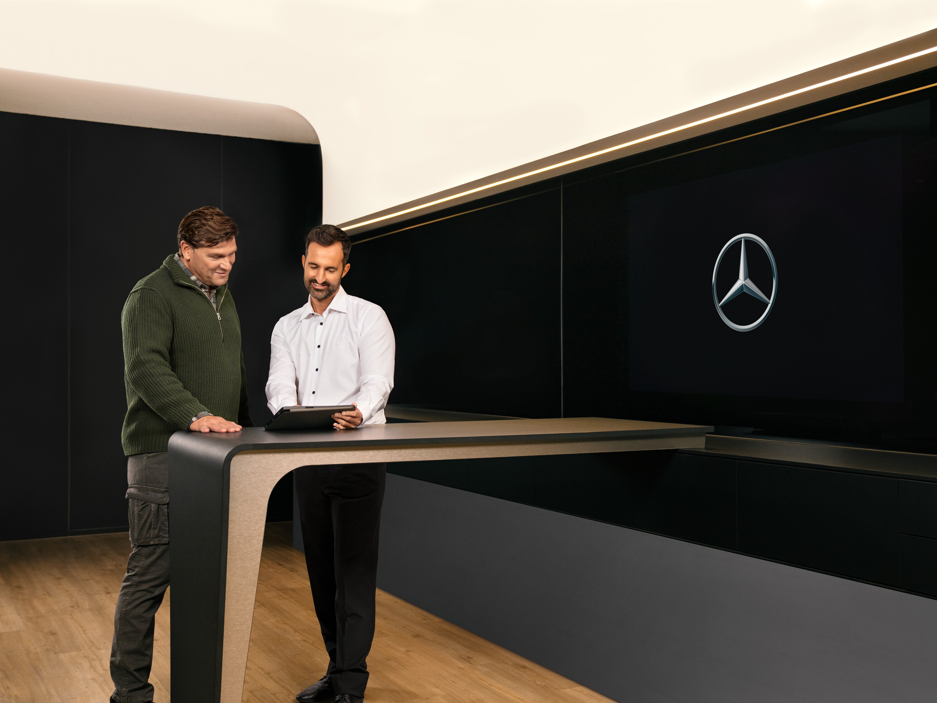Dos hombres con una tablet, conversando sobre el servicio para vehículos industriales de Mercedes-Benz .