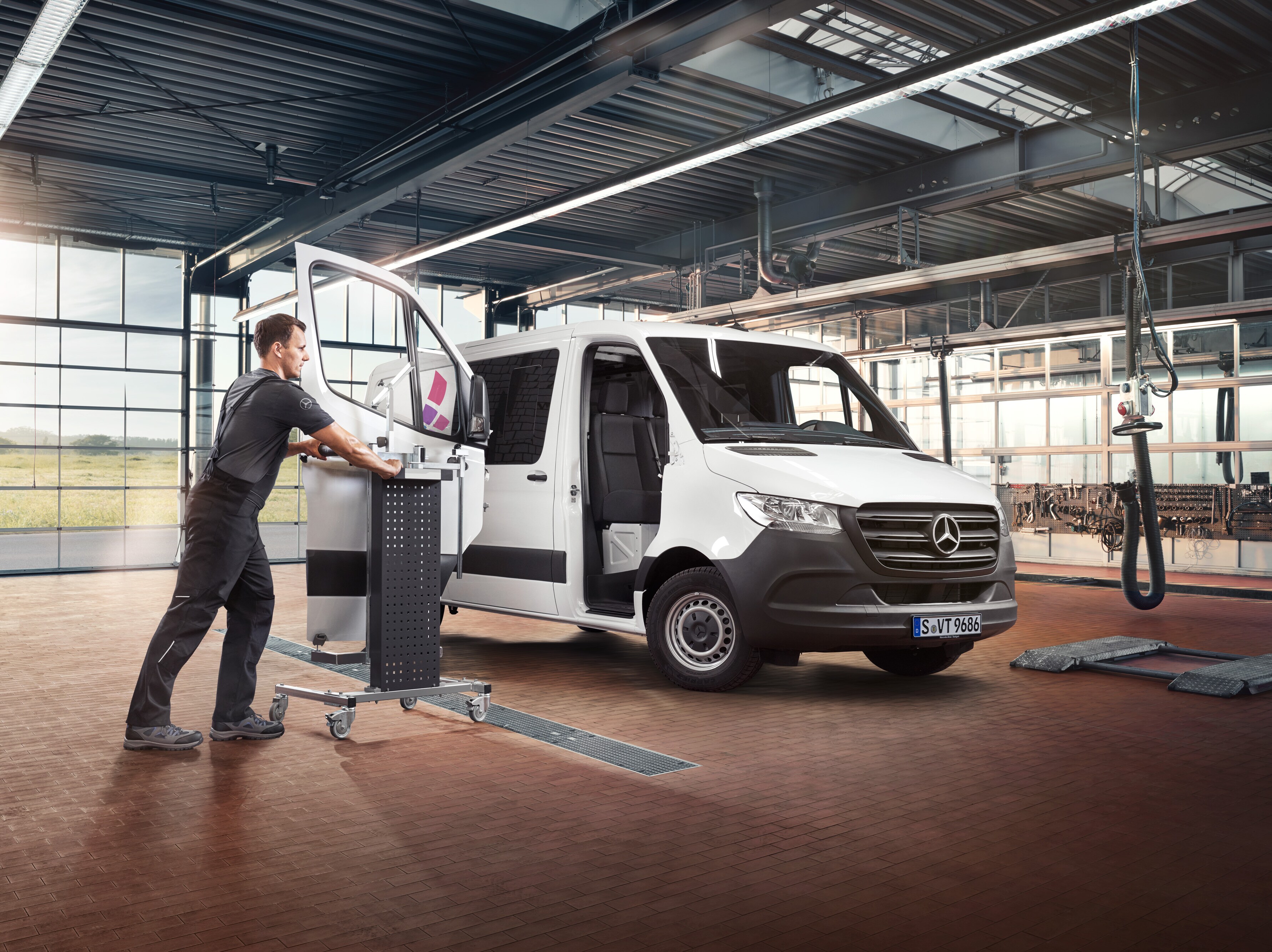 Un técnico realizando mantenimiento de la puerta del acompañante de un furgón Mercedes-Benz Sprinter blanco.