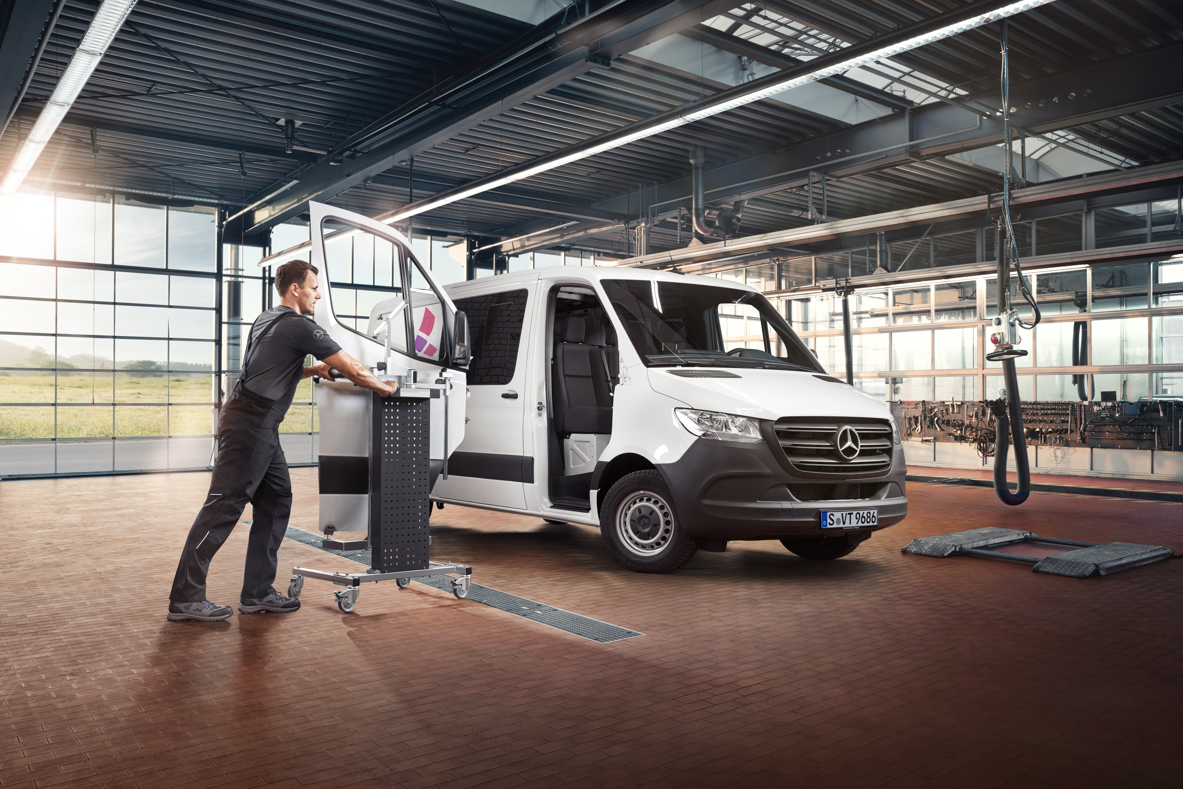 Mercedes-Benz | Servicios - vista general | Reparación Un técnico realizando mantenimiento de la puerta del acompañante de un furgón Mercedes-Benz Sprinter blanco.