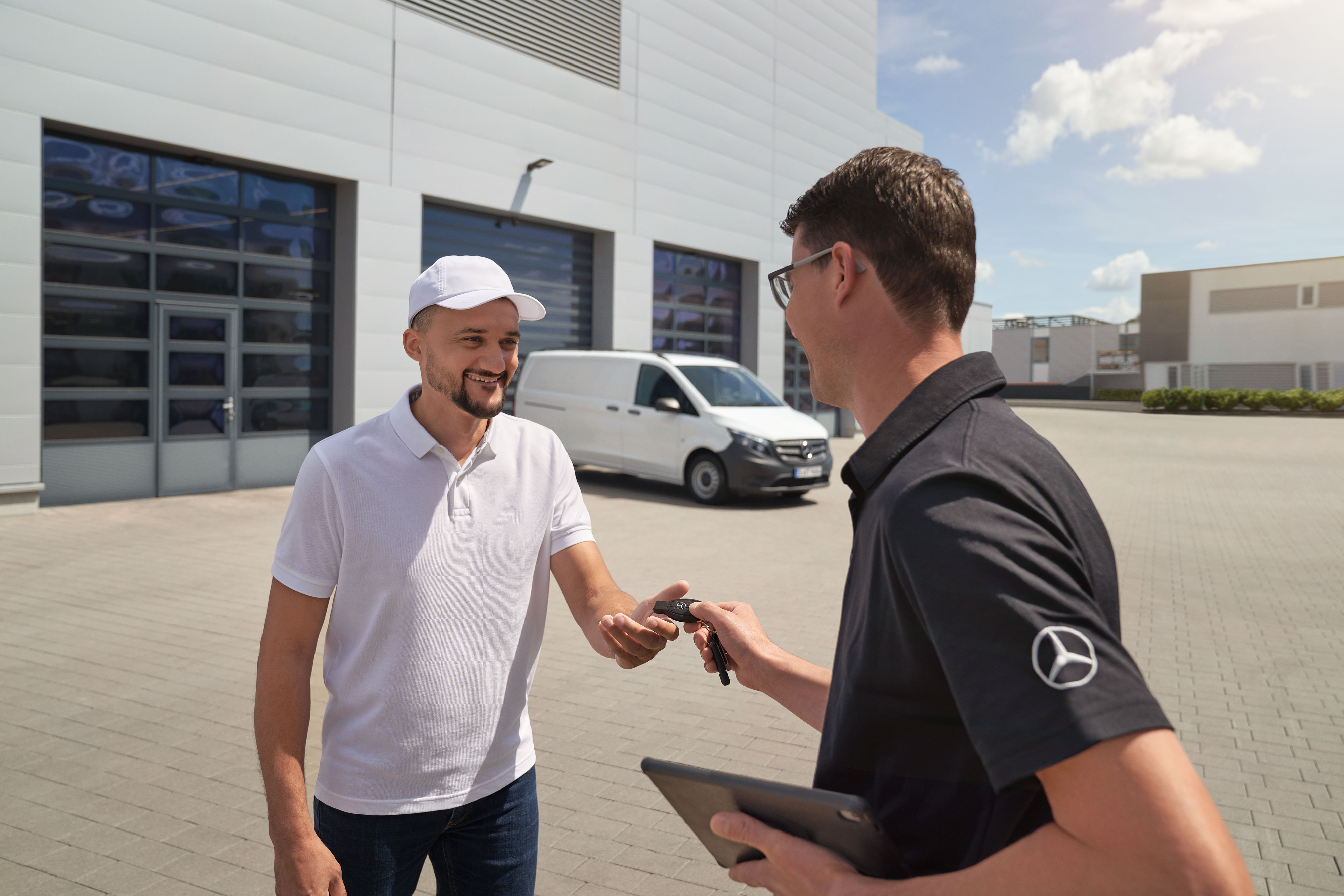 Mercedes-Benz | Van ServiceCare | Opciones adicionales Un técnico entrega el llavero a un cliente con un furgón Mercedes-Benz Vito blanco al fondo.