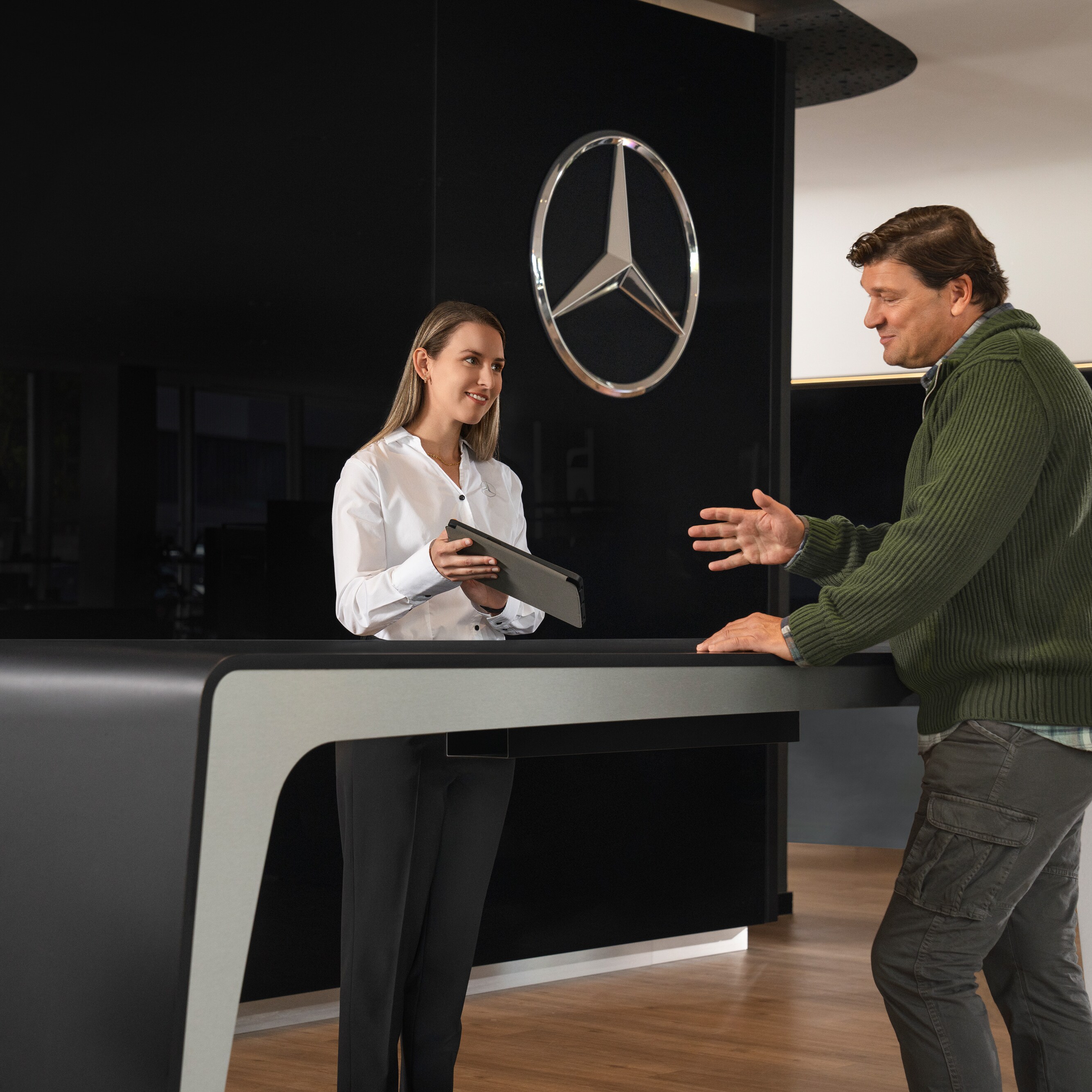 Un asesor de Mercedes-Benz dando información personalizada a unos clientes .