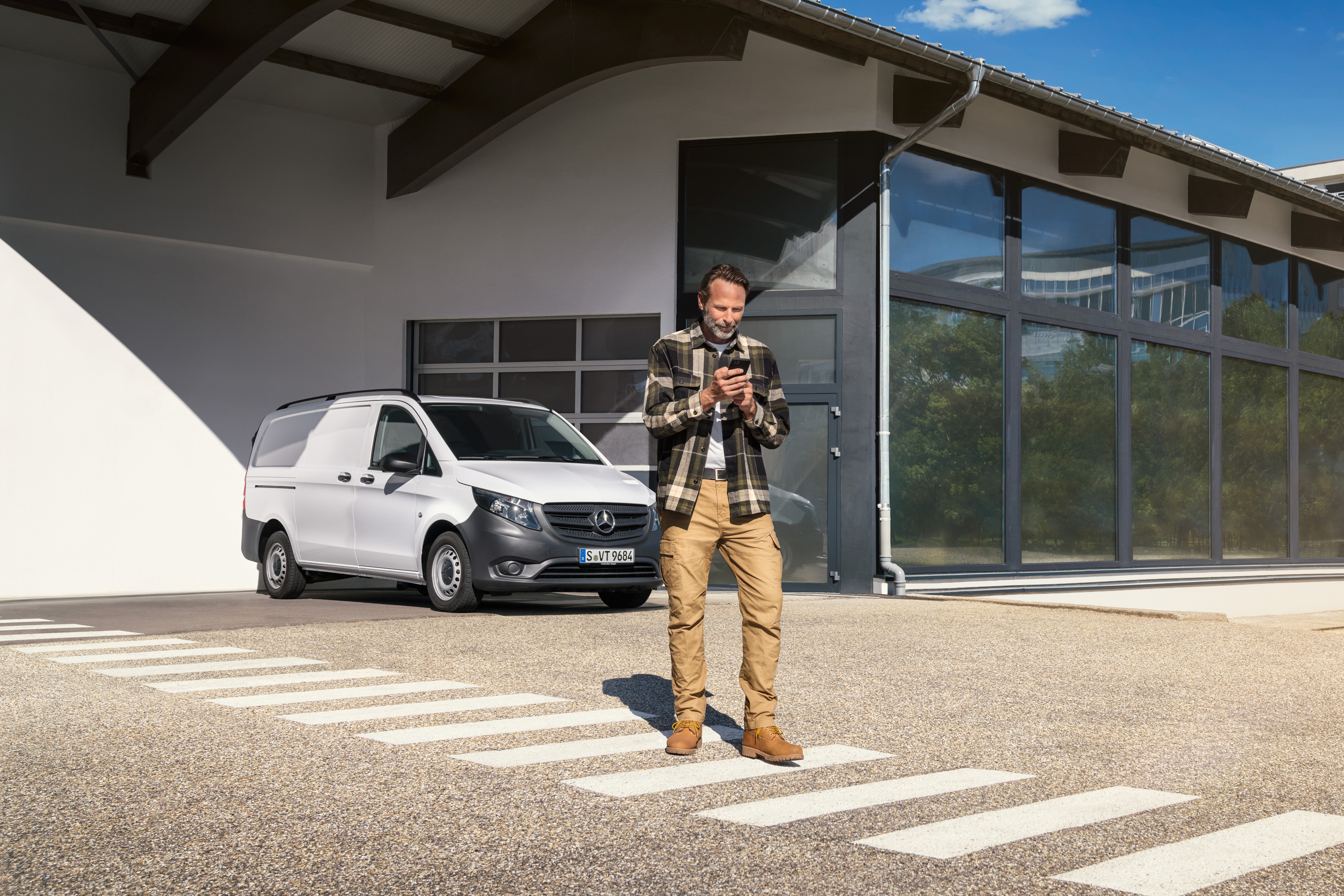 Mercedes-Benz | Servicio para vehículos eléctricos | Soporte digital Un hombre delante de un furgón Mercedes-Benz Vito blanco utilizando su smartphone.