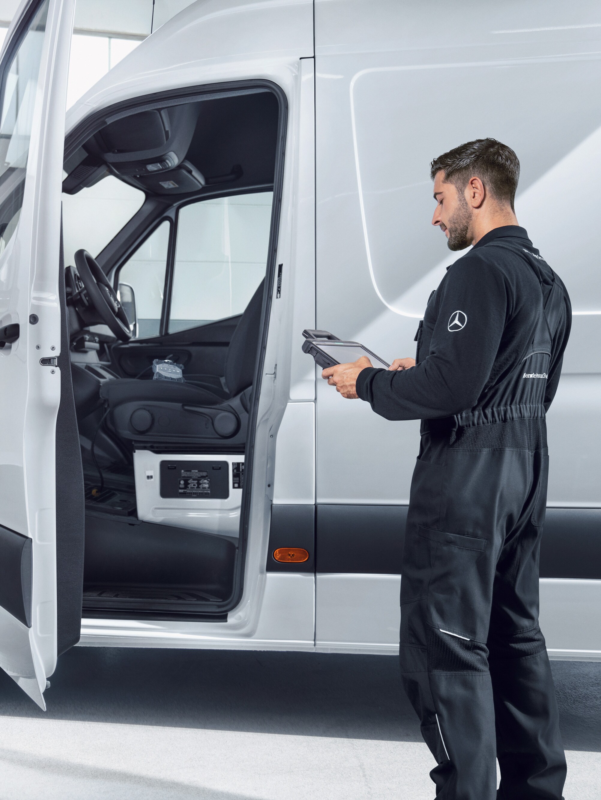 Un técnico revisando un furgón Mercedes-Benz Sprinter blanco con una tablet.
