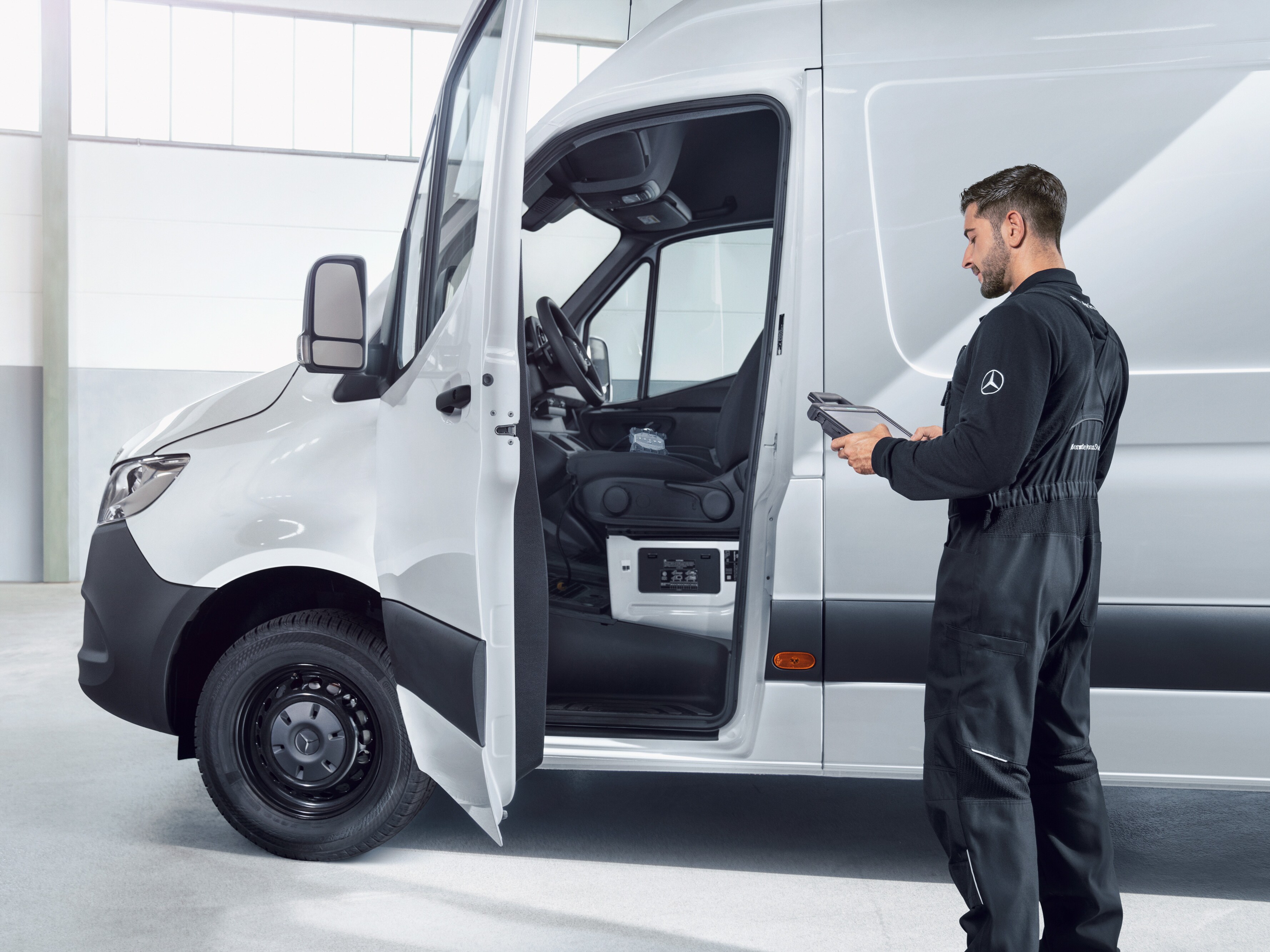 Un empleado inspeccionando un furgón Mercedes-Benz, proveyendo calidad de servicio fiable para mantenimiento y reparaciones.