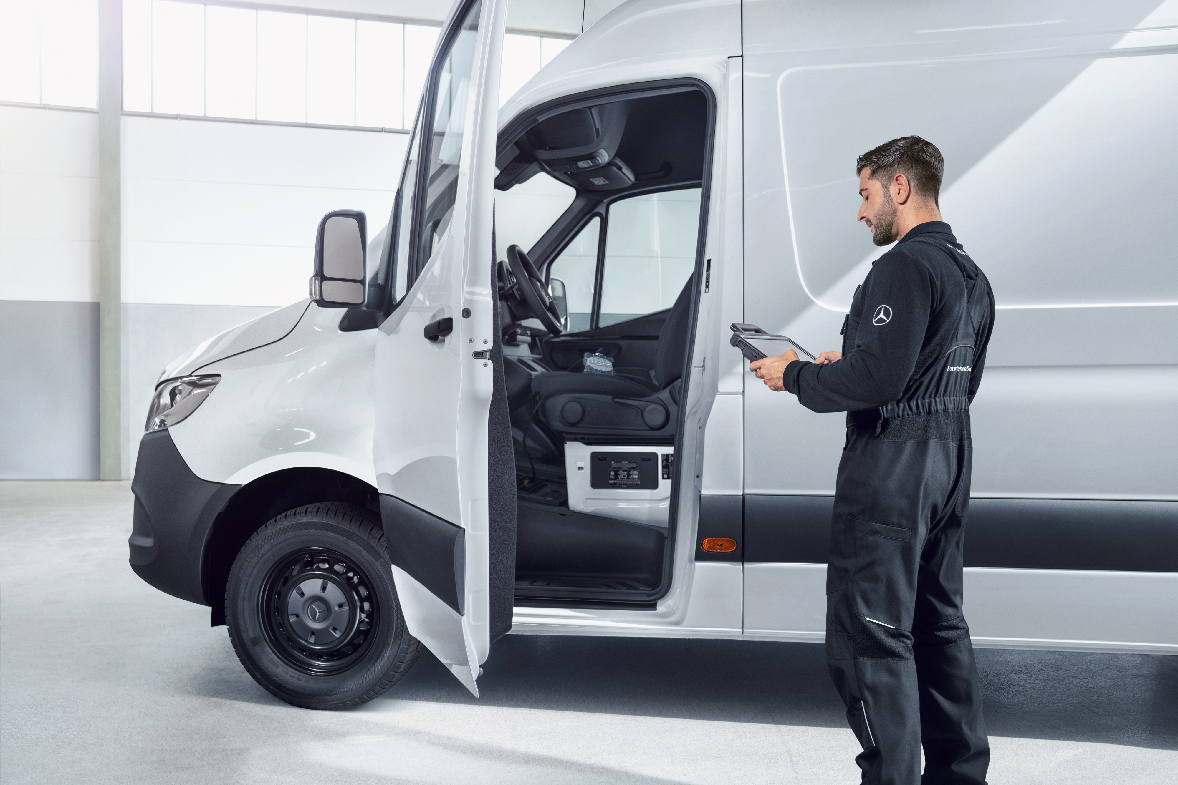 Mercedes-Benz | Servicios - vista general | Mantenimiento de vehículos Un empleado inspeccionando un furgón Mercedes-Benz, proveyendo calidad de servicio fiable para mantenimiento y reparaciones.