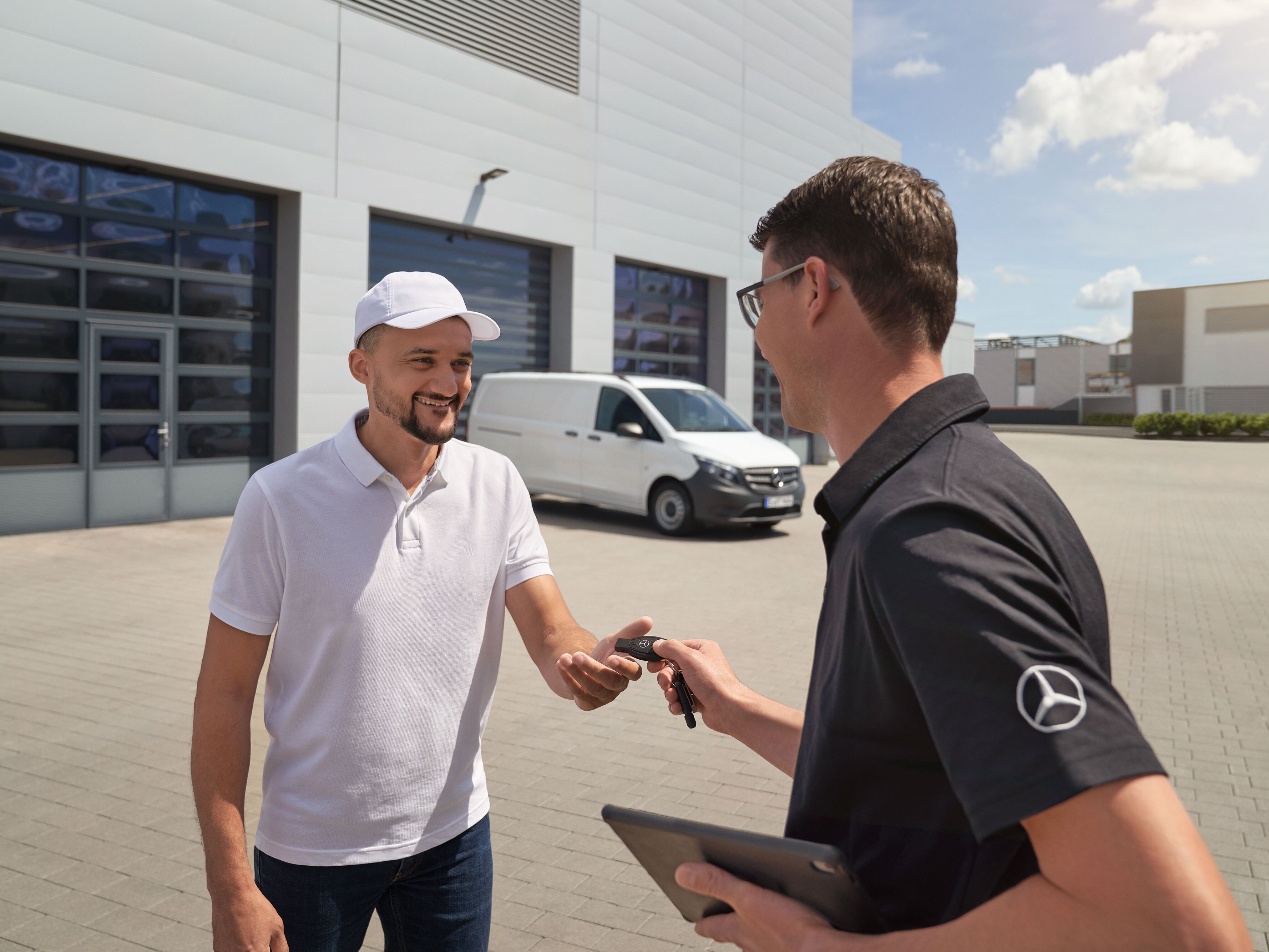Representante del servicio técnico de Mercedes-Benz entregando las llaves a un cliente con un furgón Mercedes-Benz Vito blanco al fondo.