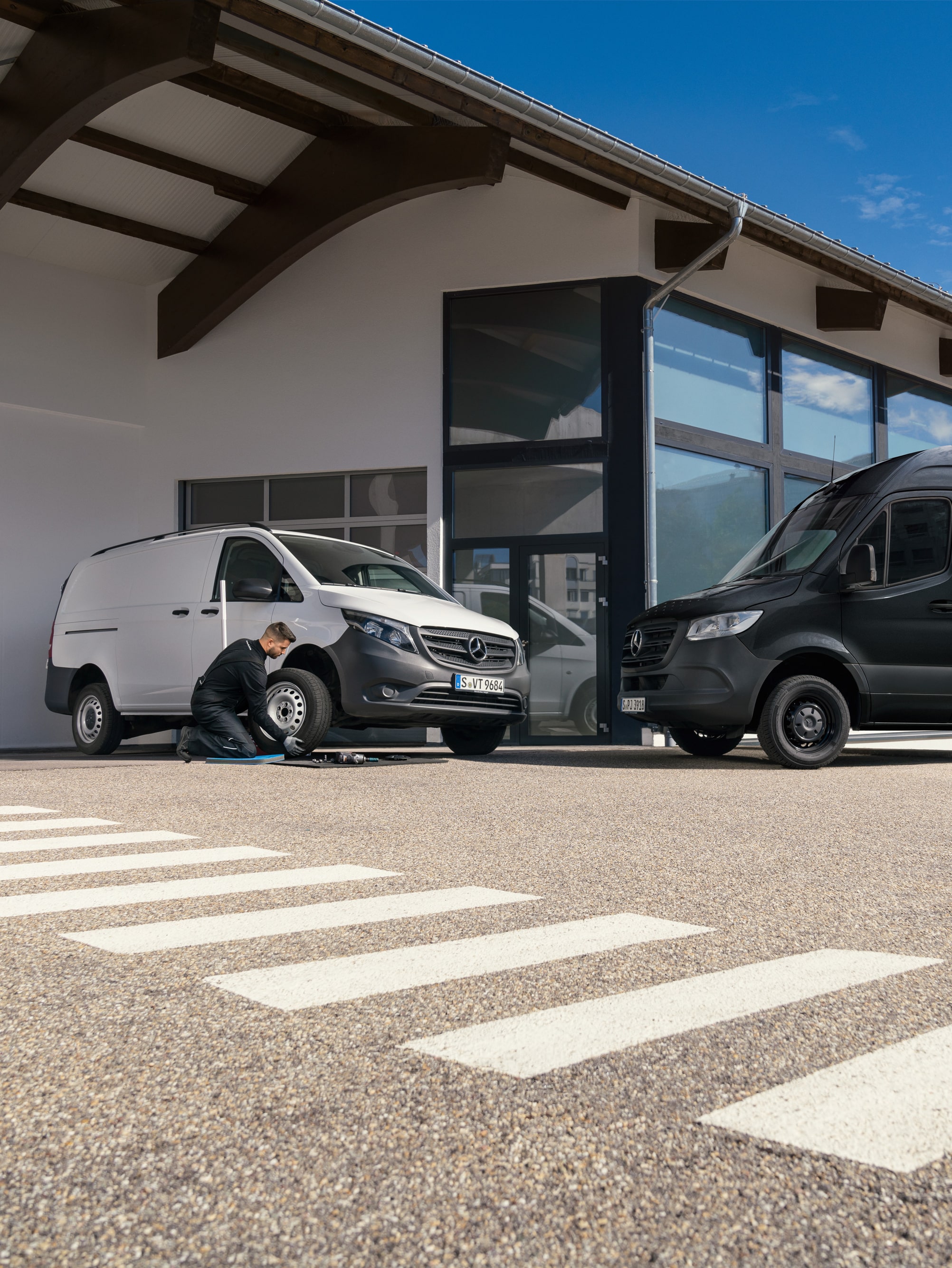 Un técnico cambiando un neumático de un furgón Mercedes-Benz Vito blanco delante de una sala de exposiciones.