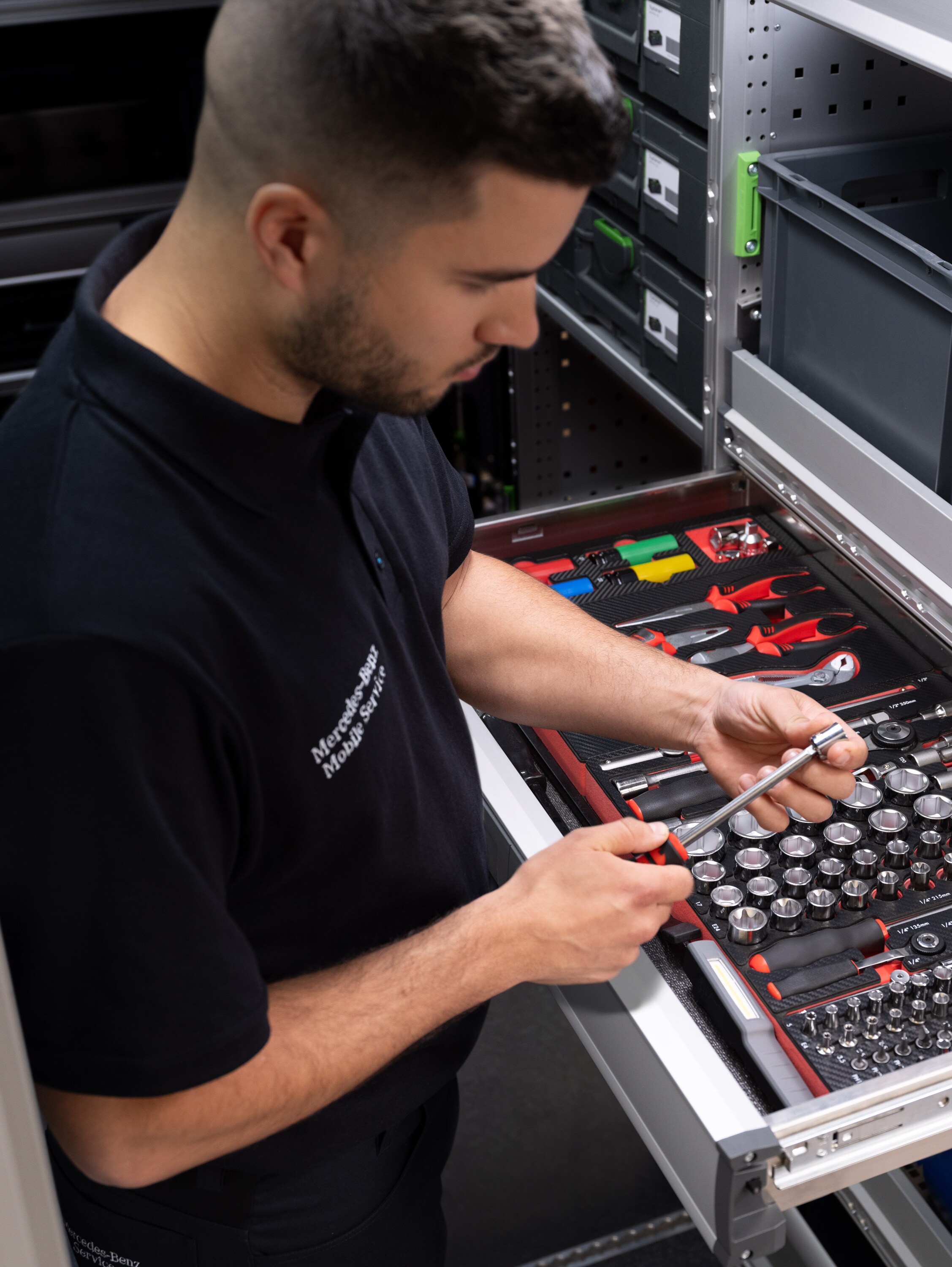 Un técnico eligiendo un artículo de un cajón lleno de herramientas.