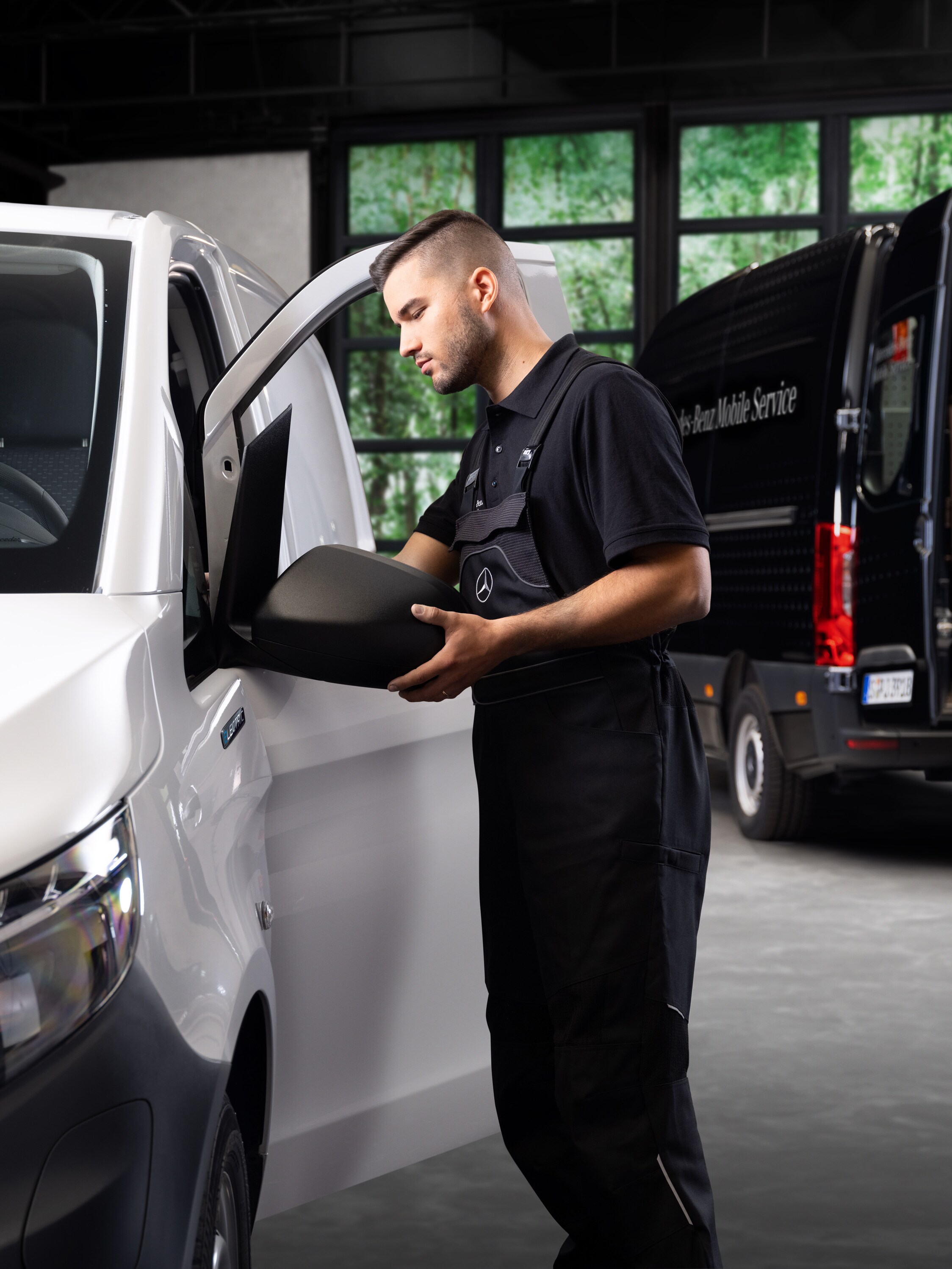 Un técnico sustituye un retrovisor exterior en un furgón Mercedes-Benz Vito blanco.