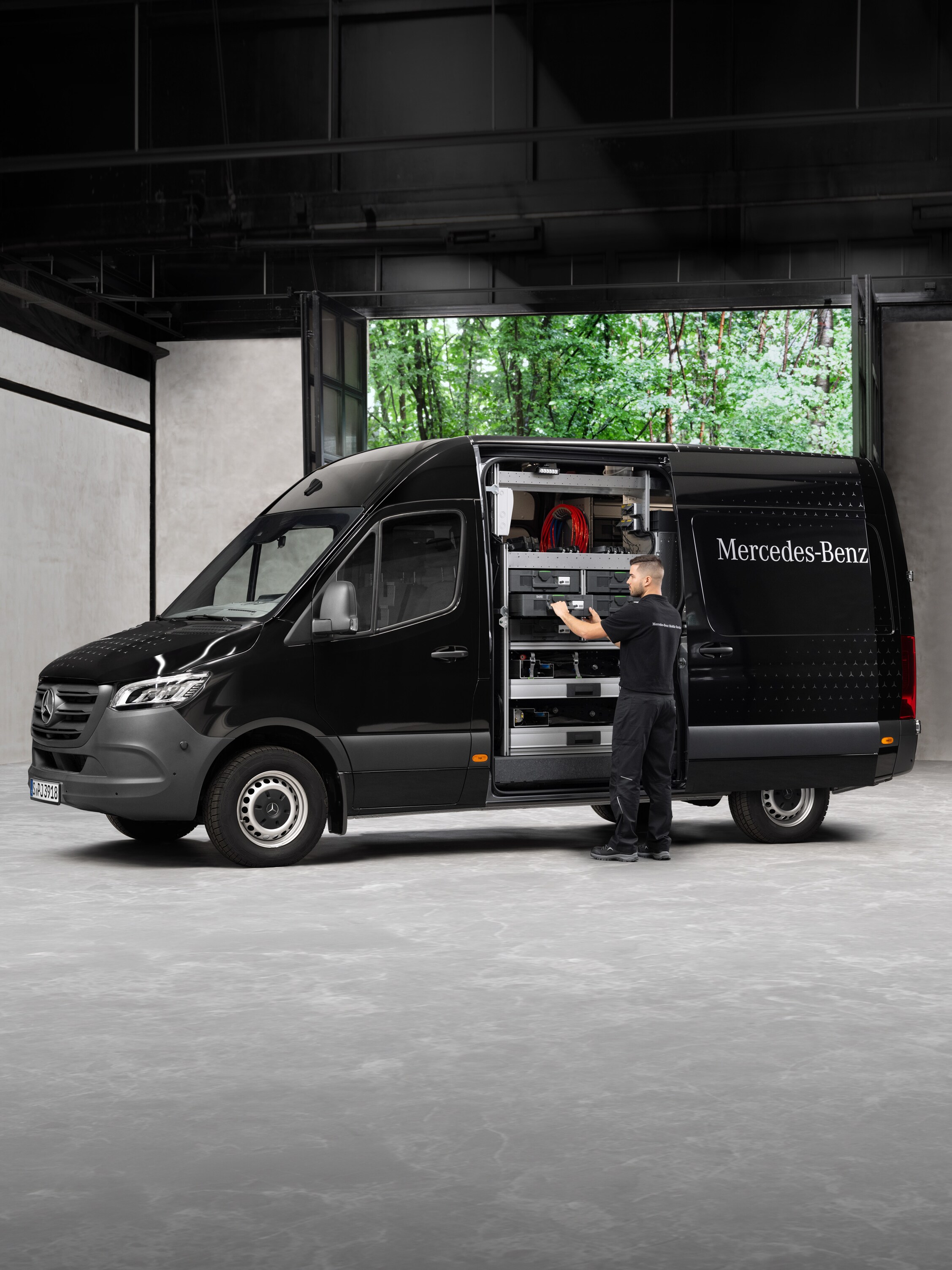 Un técnico retirando herramientas de un furgón Mercedes-Benz Sprinter negro.