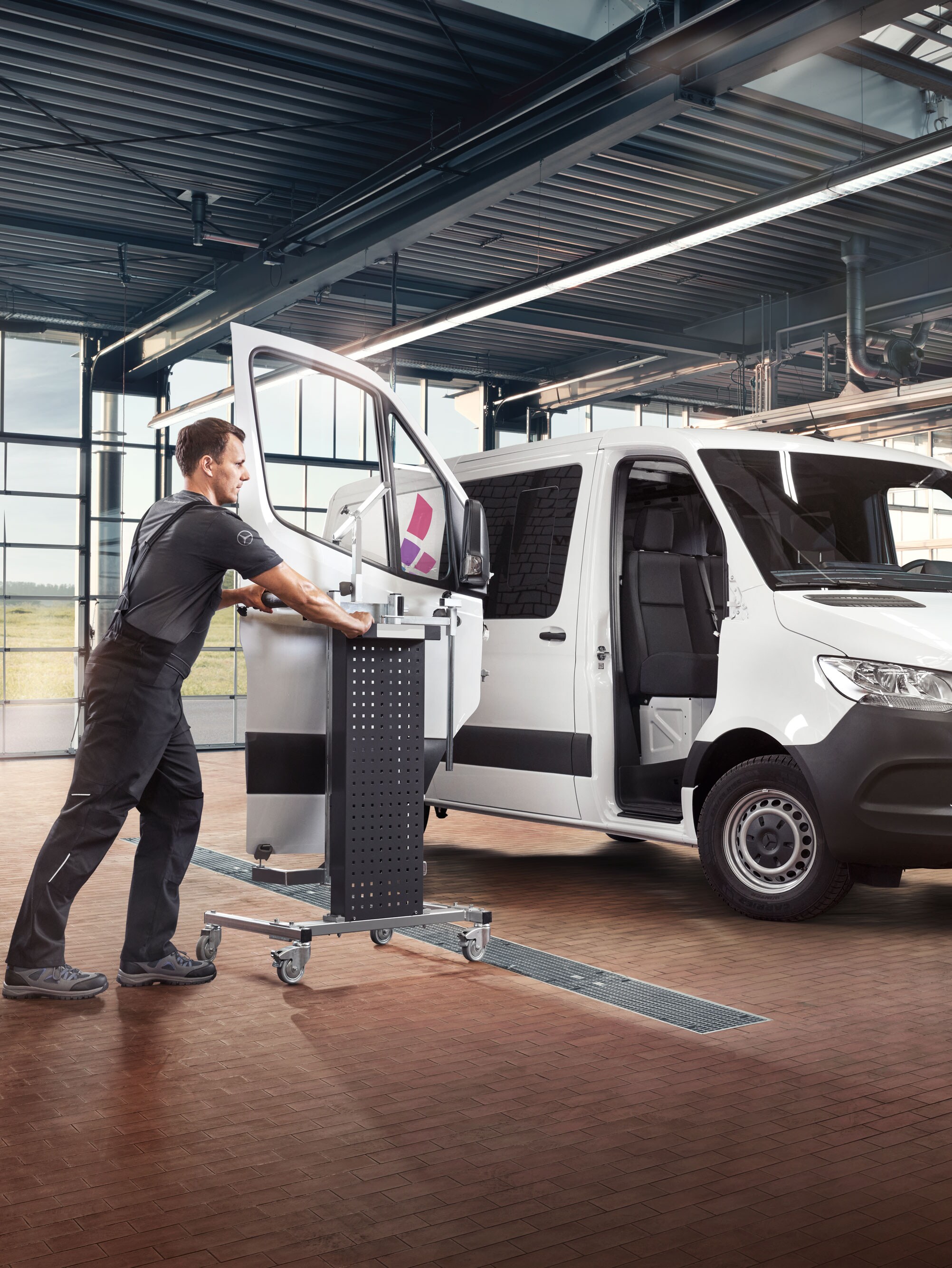 Mecánico instalando la puerta de un Mercedes-Benz Sprinter blanco.