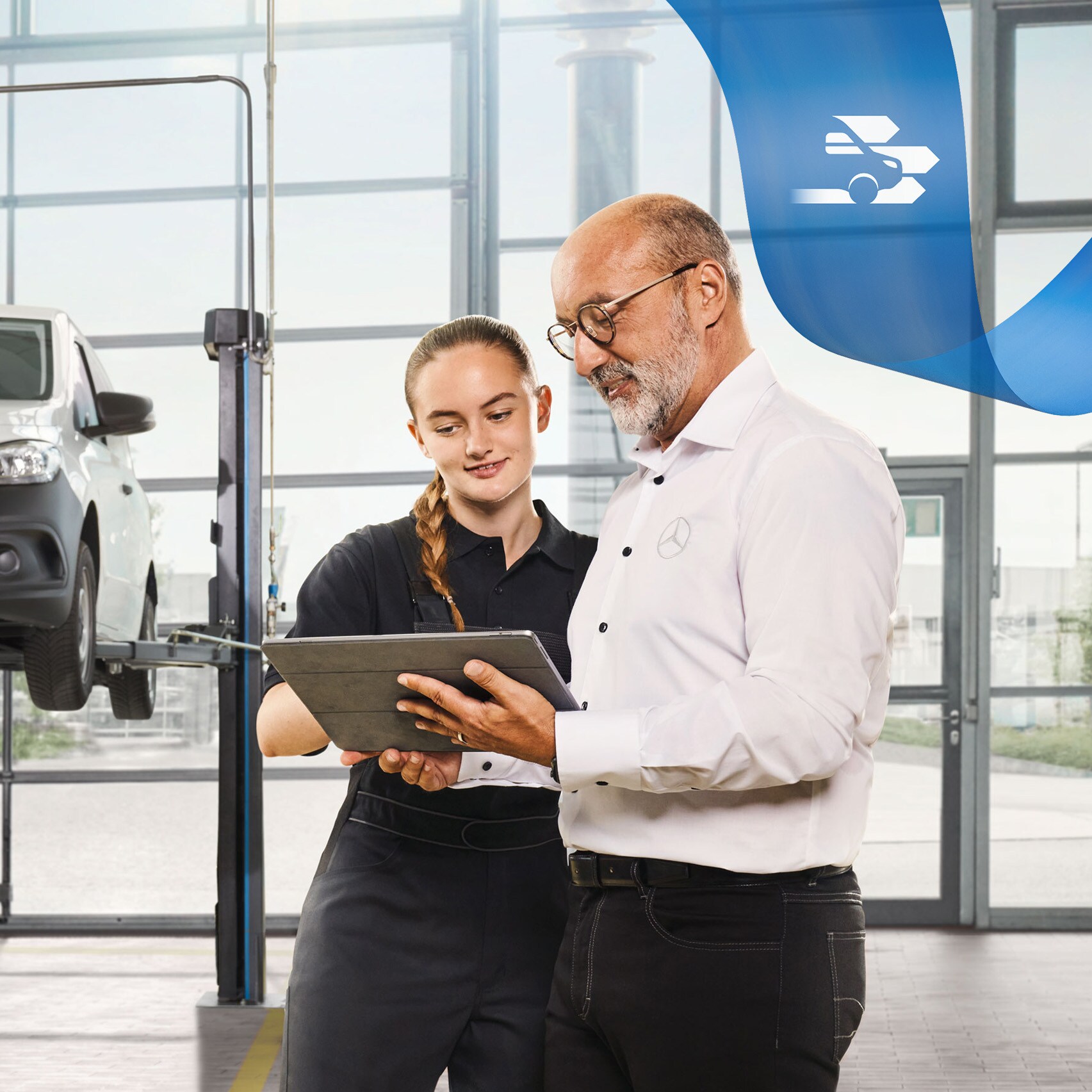 Dos empleados conversando sobre el servicio de vehículos industriales en un furgón Mercedes-Benz levantado con un gato en el taller.