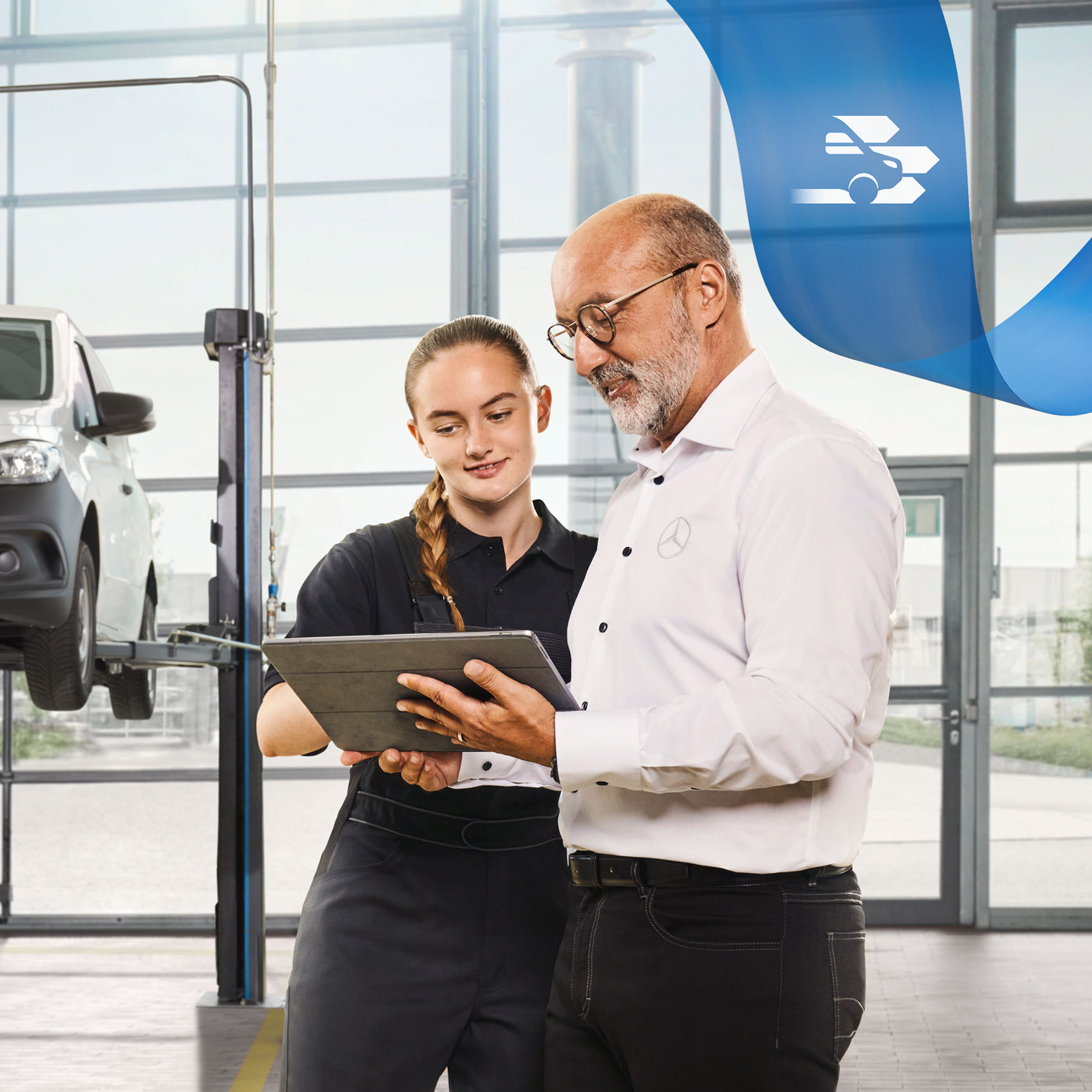 Mercedes-Benz | Mantenimiento Dos empleados conversando sobre el servicio de vehículos industriales en un furgón Mercedes-Benz levantado con un gato en el taller.