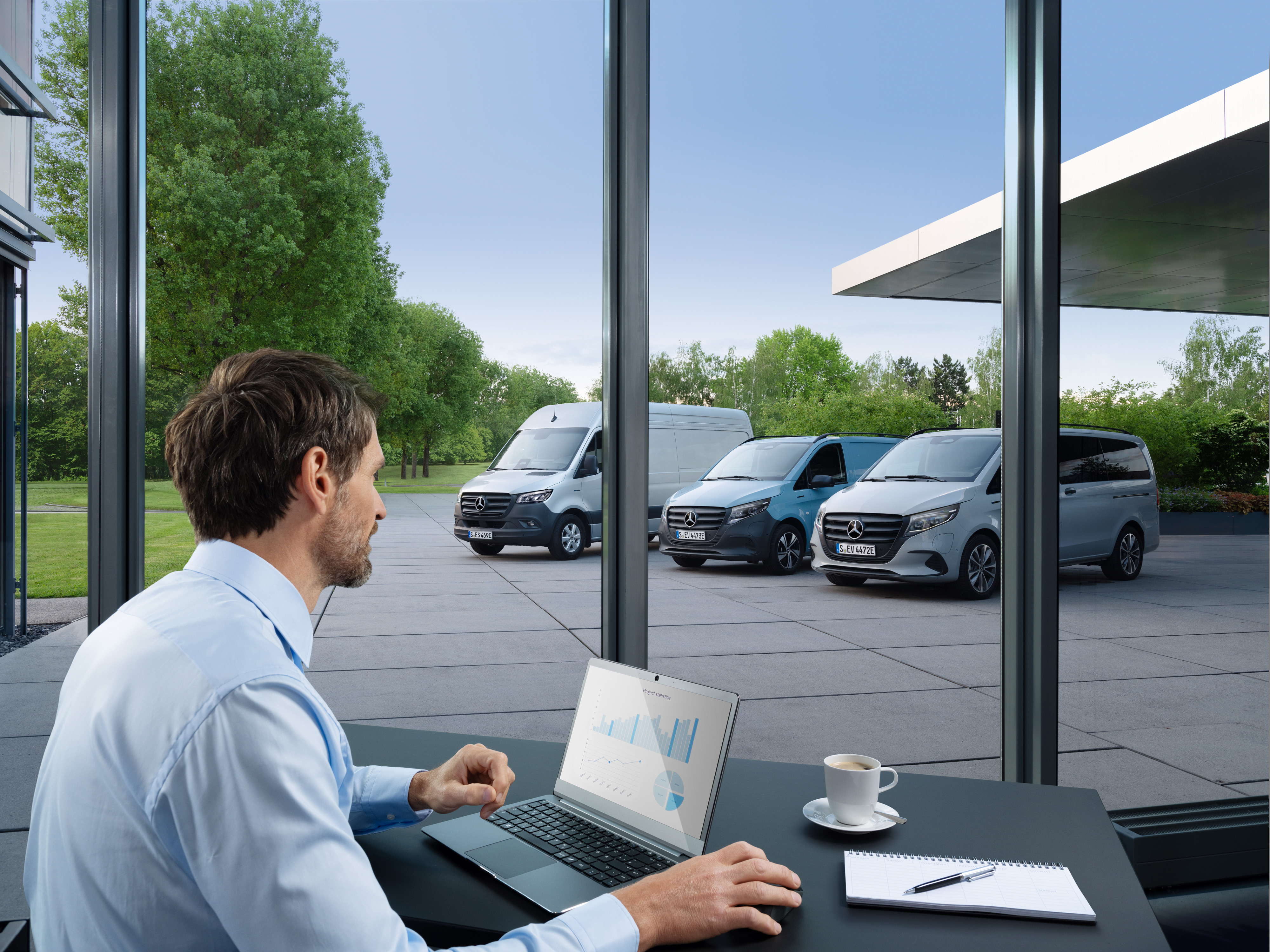 Mercedes-Benz | Tecnología para furgones | Van Uptime Monitor Hombre monitoreando con un portátil varios furgones Mercedes-Benz aparcados, símbolo de la gestión digital de flotas.