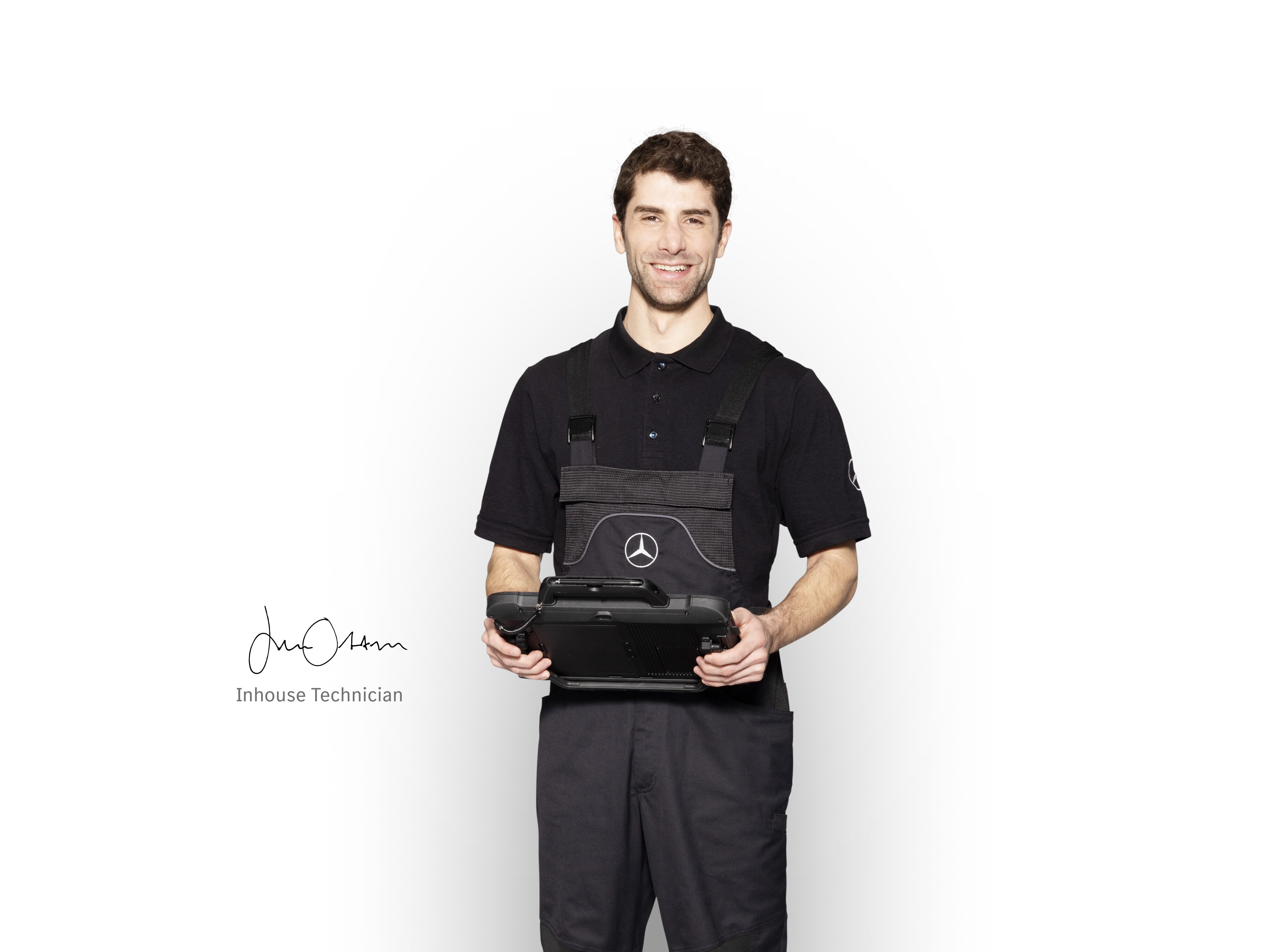 Mecánico interno de Mercedes-Benz en ropa de trabajo sosteniendo una tablet preparada para la notificación de daños.