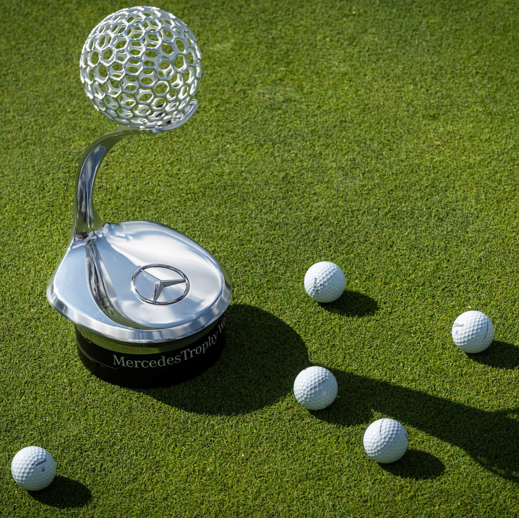 Imagen del trofeo del MercedesTrophy con pelotas de golf alrededor