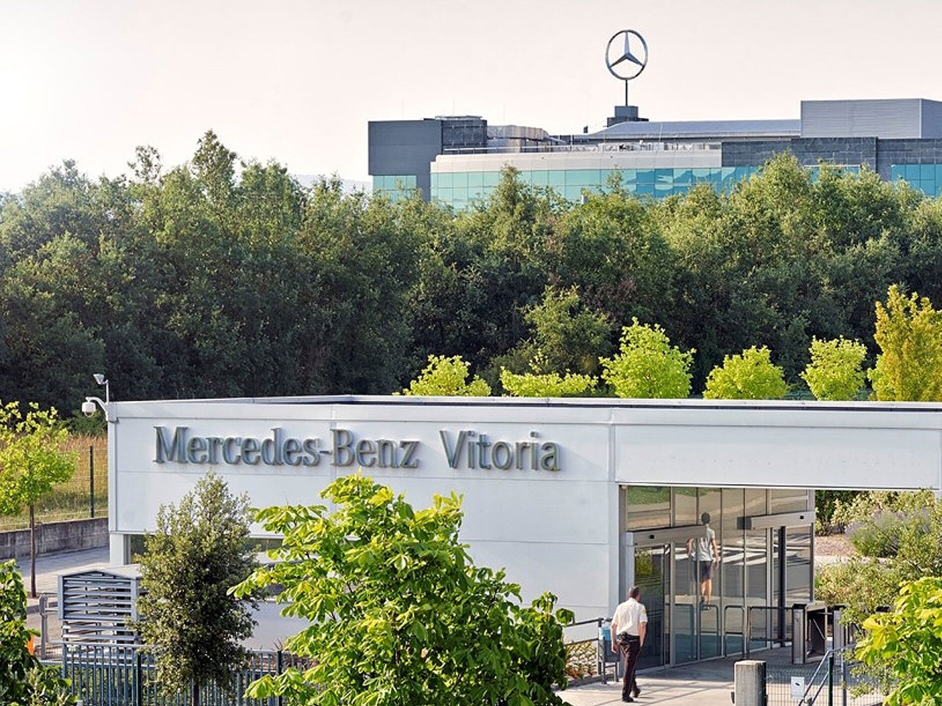 visual de la fábrica de Vitoria por fuera en color blanco y rodeada de árboles verdes