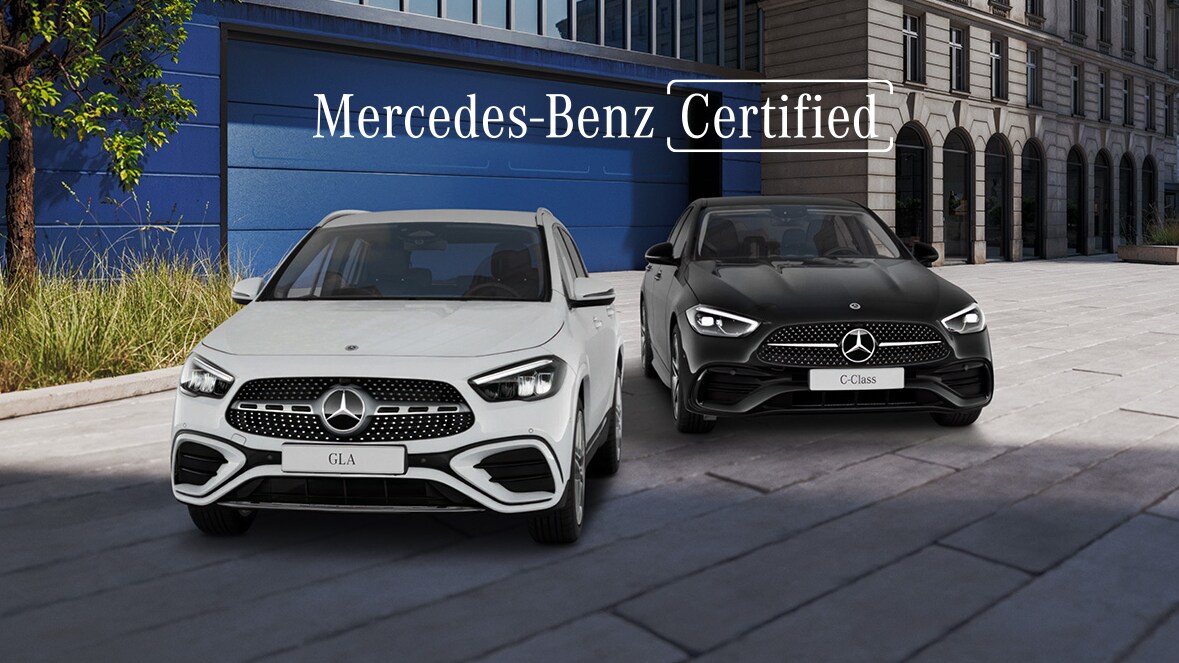 Visual frontal de un GLA blanco y un Clase C negro aparcados en la calle