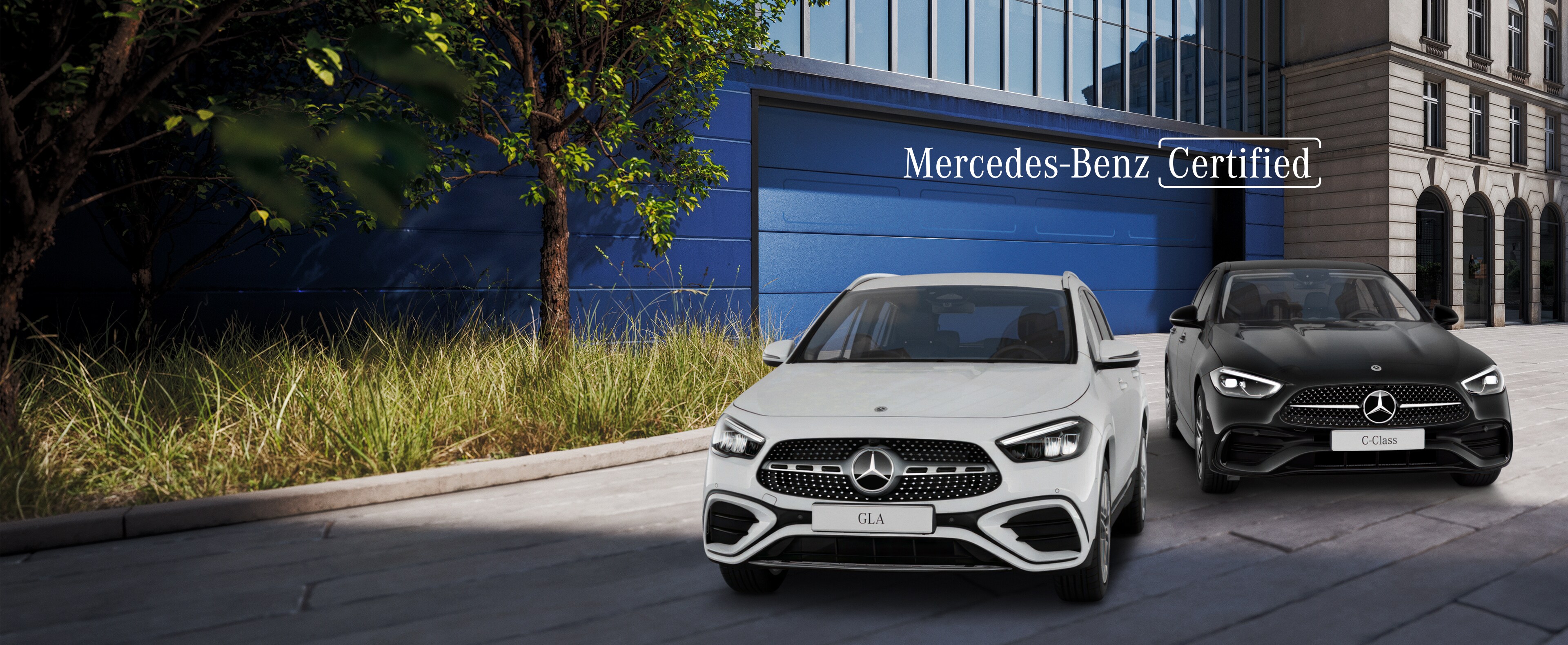 Visual frontal de un GLA blanco y un Clase C negro aparcados en la calle