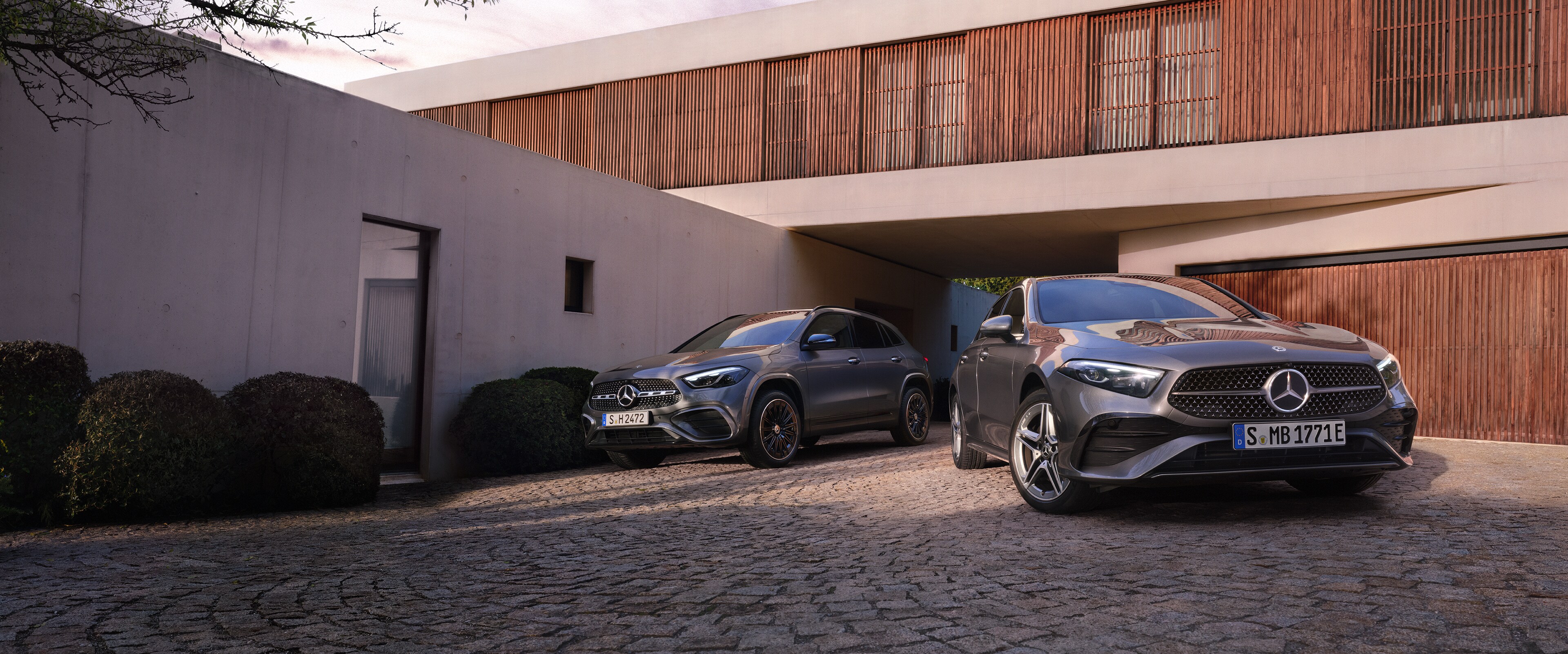 Visual frontal de un GLA y un Clase A en color gris aparcados en un parking