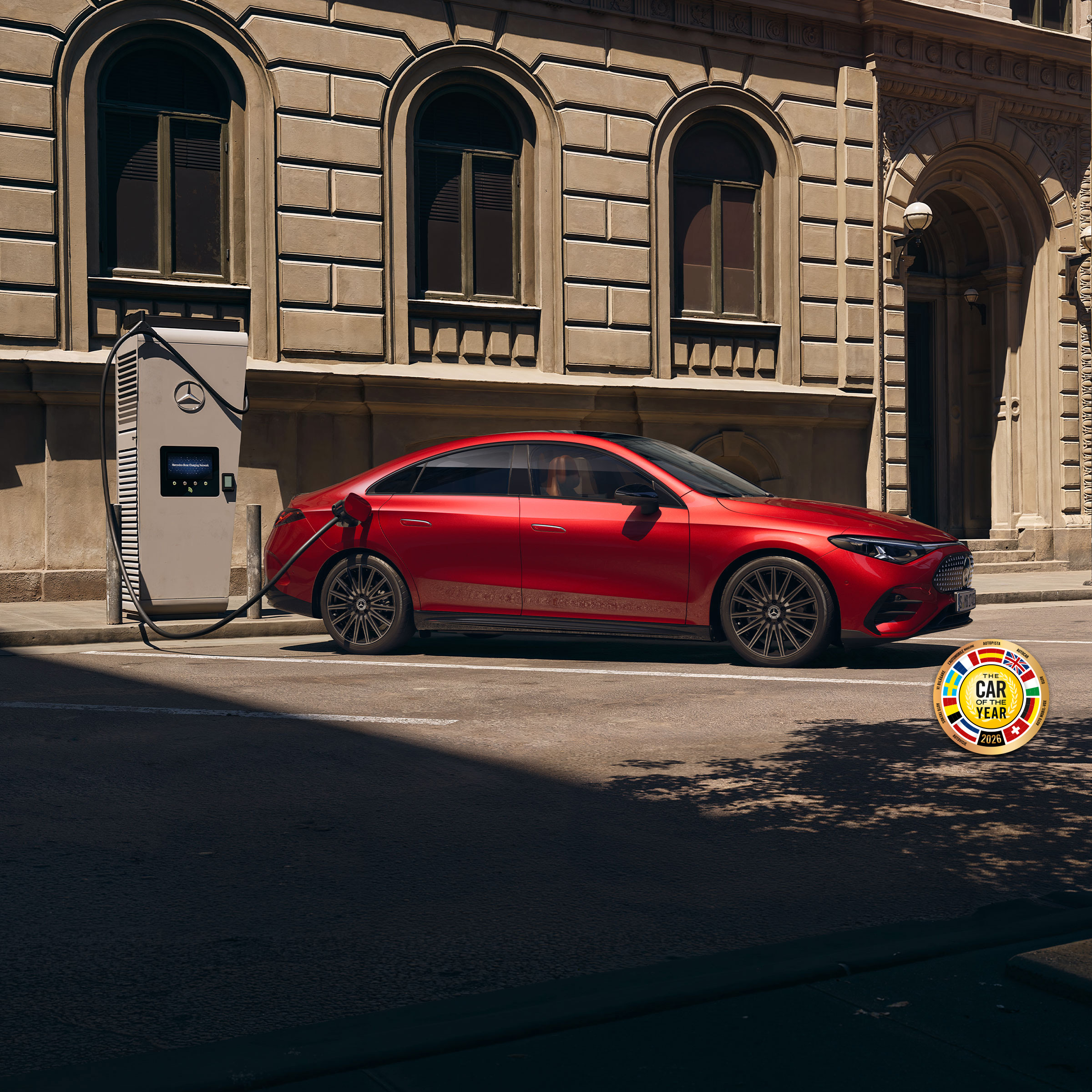 Oferta | CLA 100% eléctrico | Mercedes-Benz visual alteral del CLA eléctrico en color rojo aparcado en la calle con un cargador
