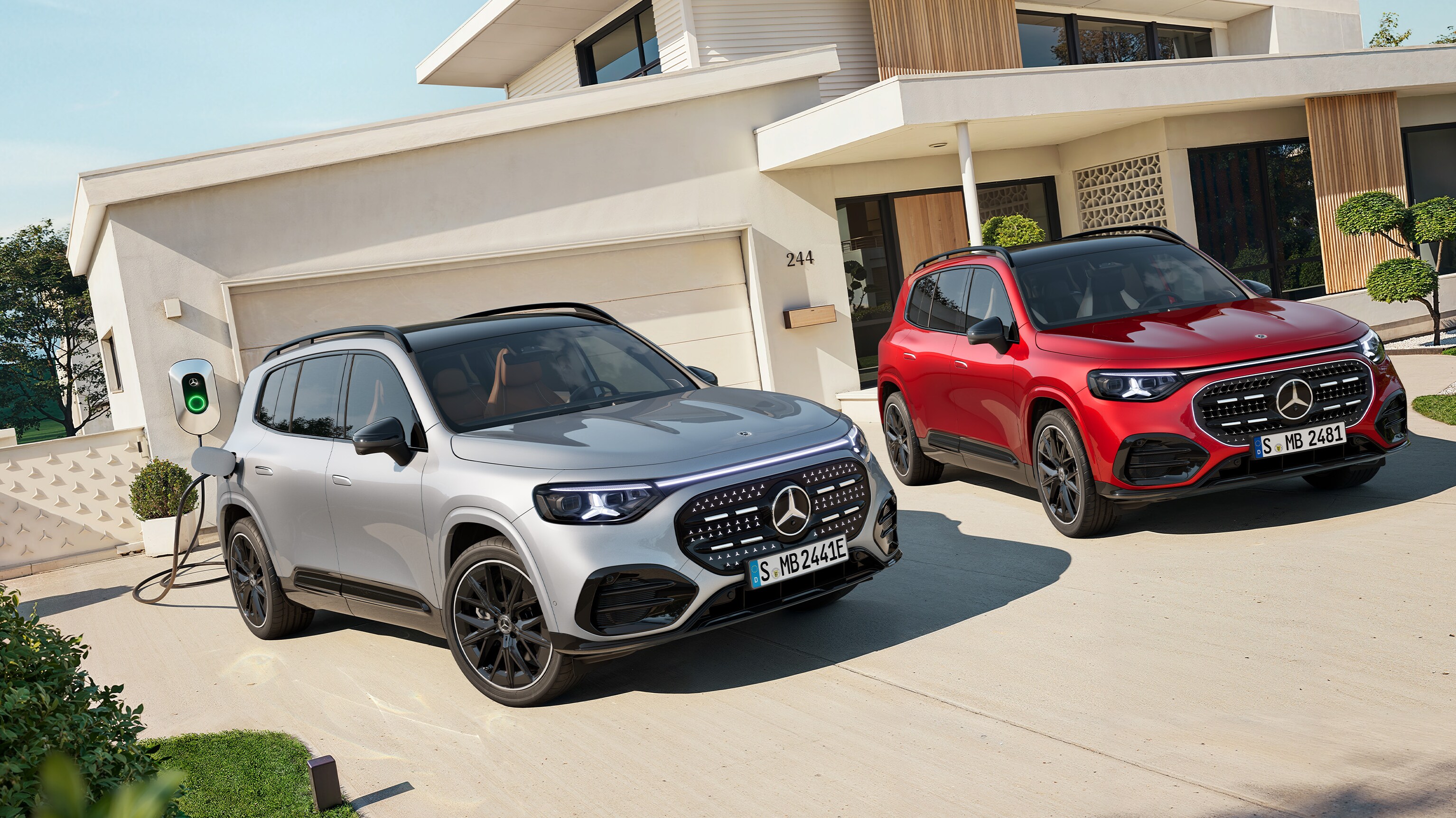 El nuevo GLB eléctrico en rojo y gris aparcado fuera de una casa