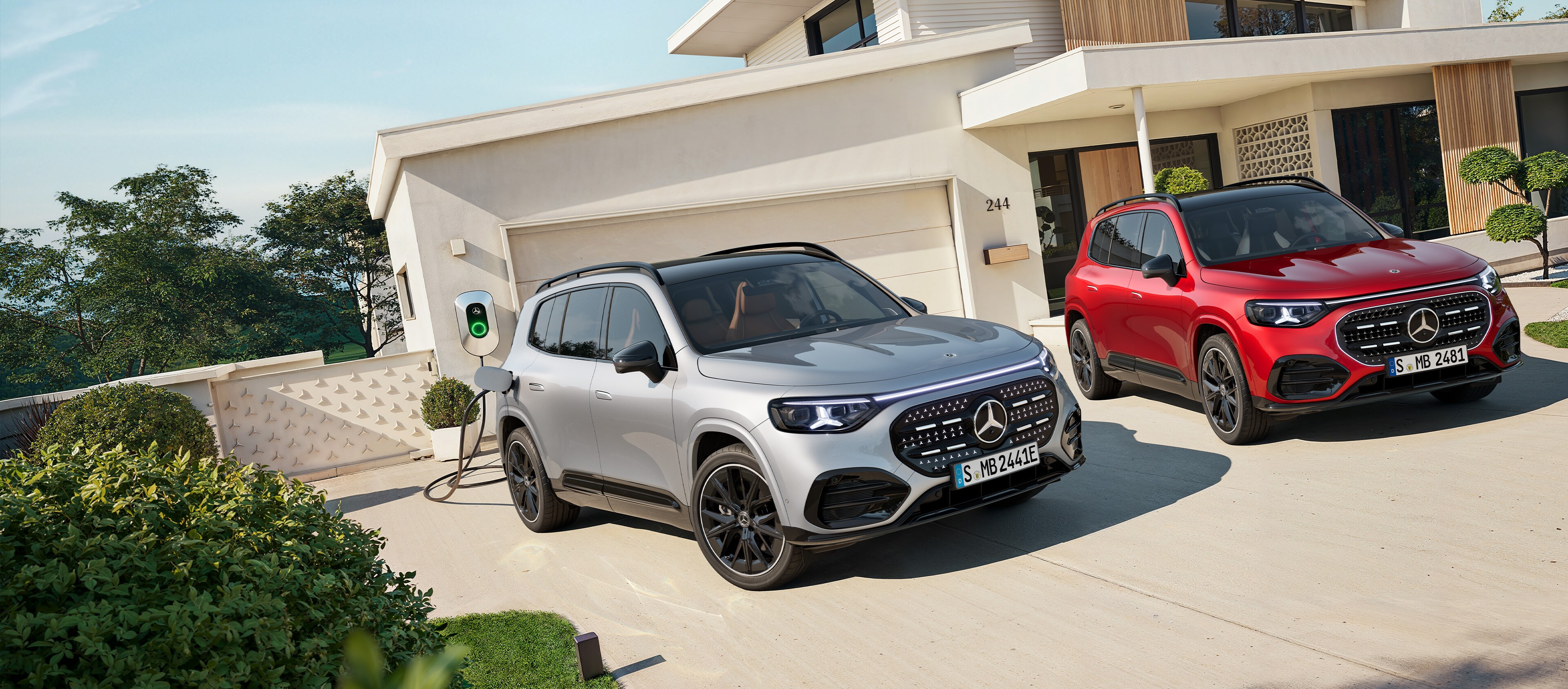 El nuevo GLB eléctrico en rojo y gris aparcados fuera de una casa