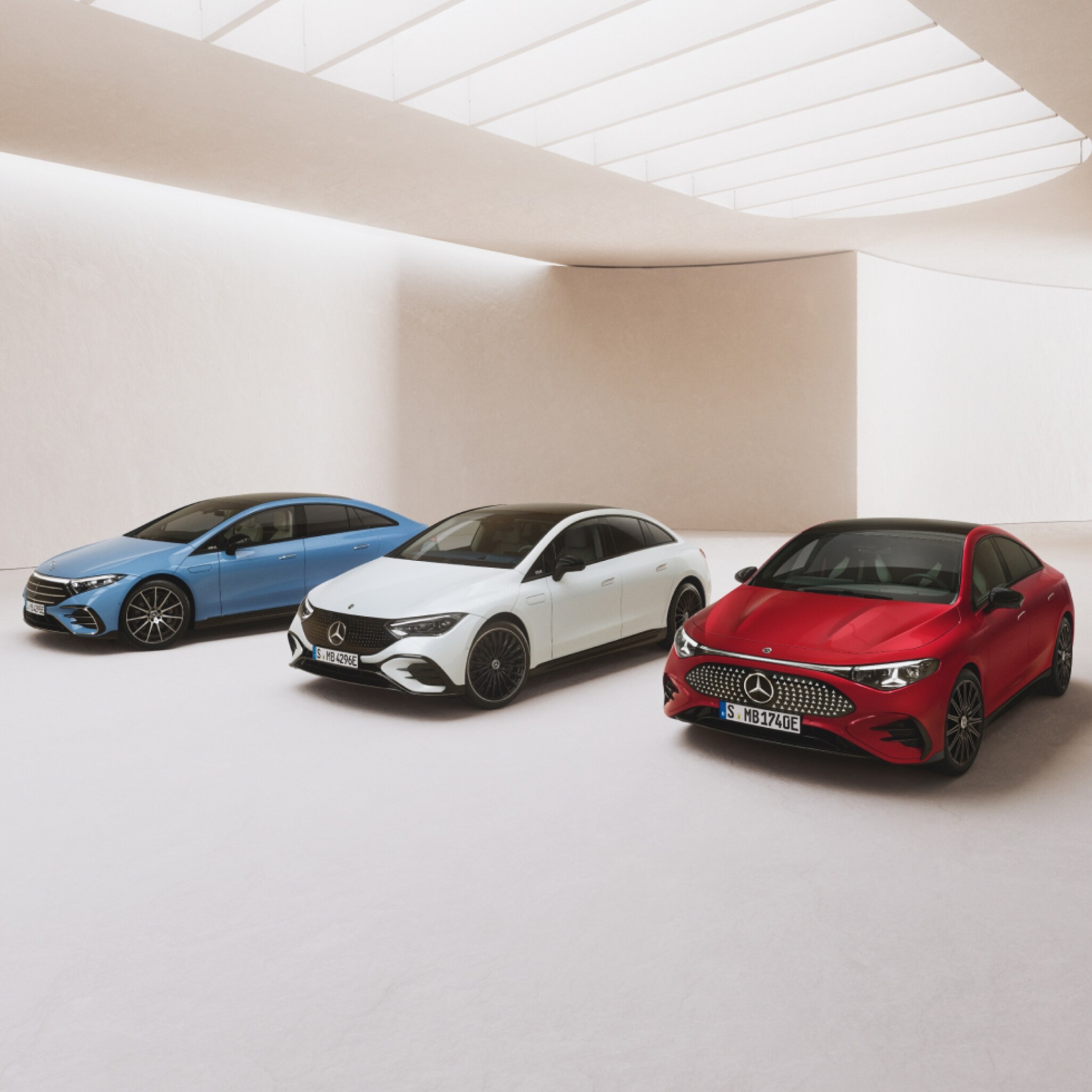 Visual de un Clase A blanco y un CLA rojo de Mercedes-Benz con una cortina roja volando sobre ellos