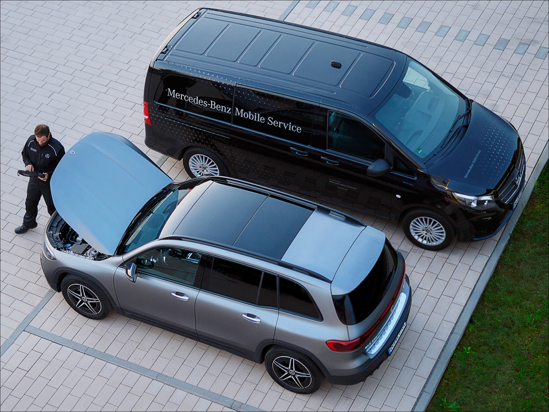 Mobile Service | Mercedes-Benz visual desde arriba de un mecánico chequeando un coche de color gris con el capó abierto