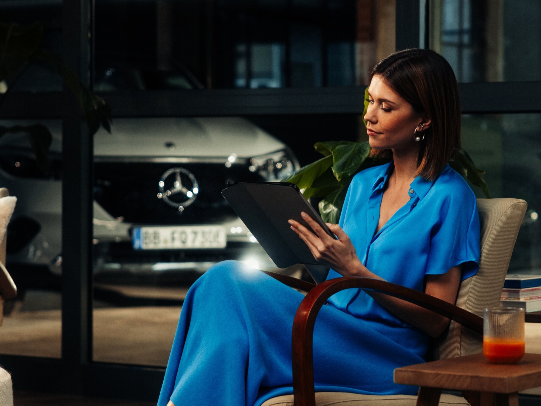 visual de una mujer vestida de azul sentada en una silla mirando una tablet 