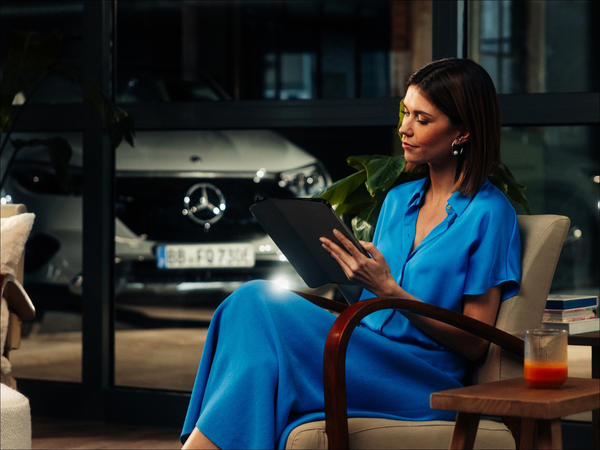 Acuerdos de servicios | Mercedes-Benz visual de una mujer vestida de azul sentada en una silla mirando una tablet