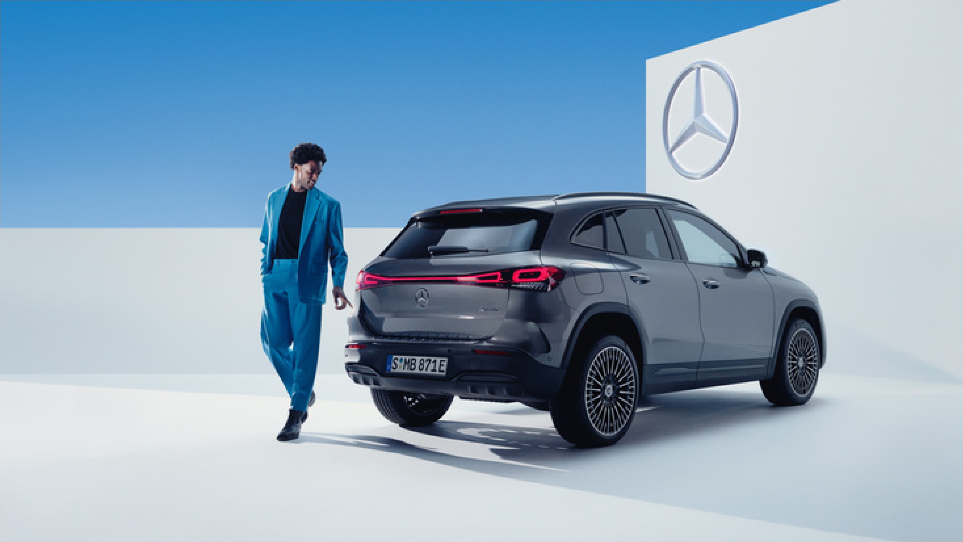 ServiCare Fit | Mercedes-Benz Un hombre con un traje azul detras de un EQ negro de Mercedes-Benz