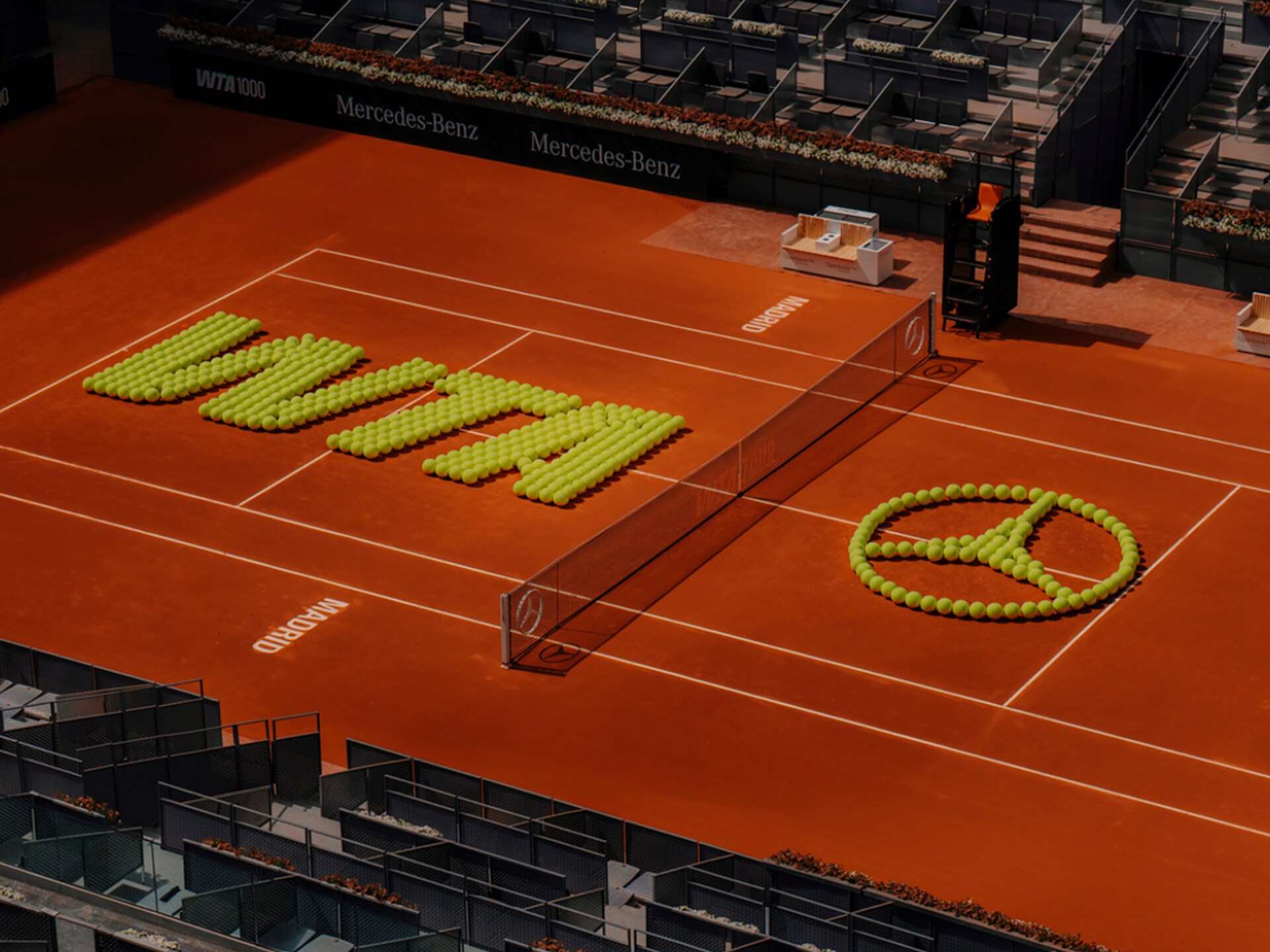 visual de una pista de tenis con el logo de WTA y Mercedes-benz creados a partir de bolas de tenis