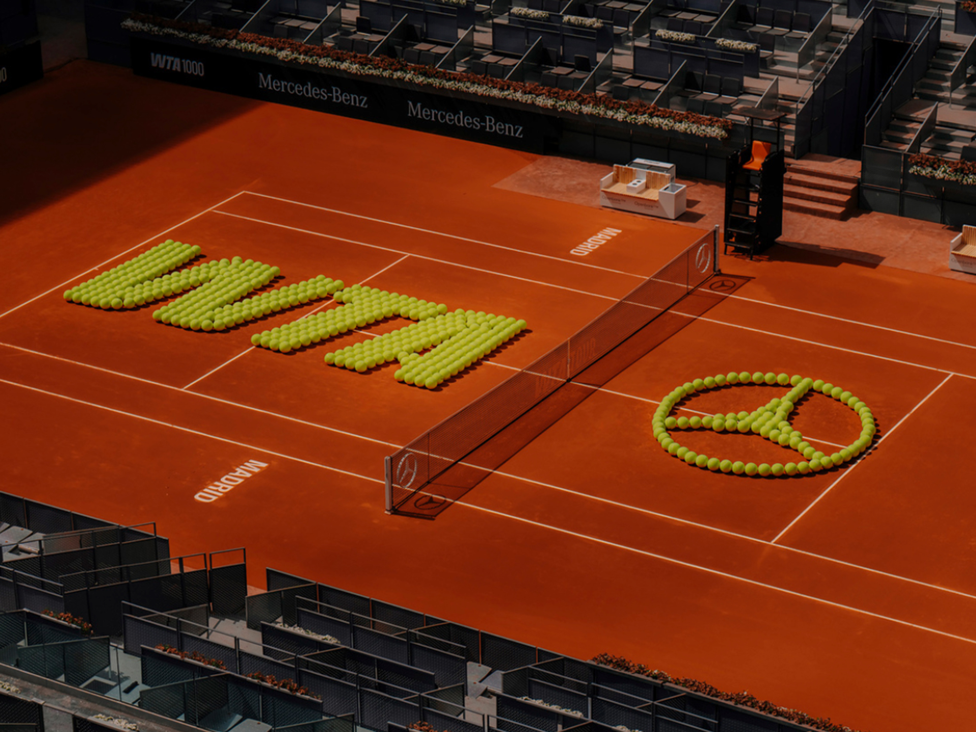 Mutua Madrid Open | Mercedes - Benz visual de una pista de tenis con el logo de WTA y Mercedes-benz creados a partir de bolas de tenis