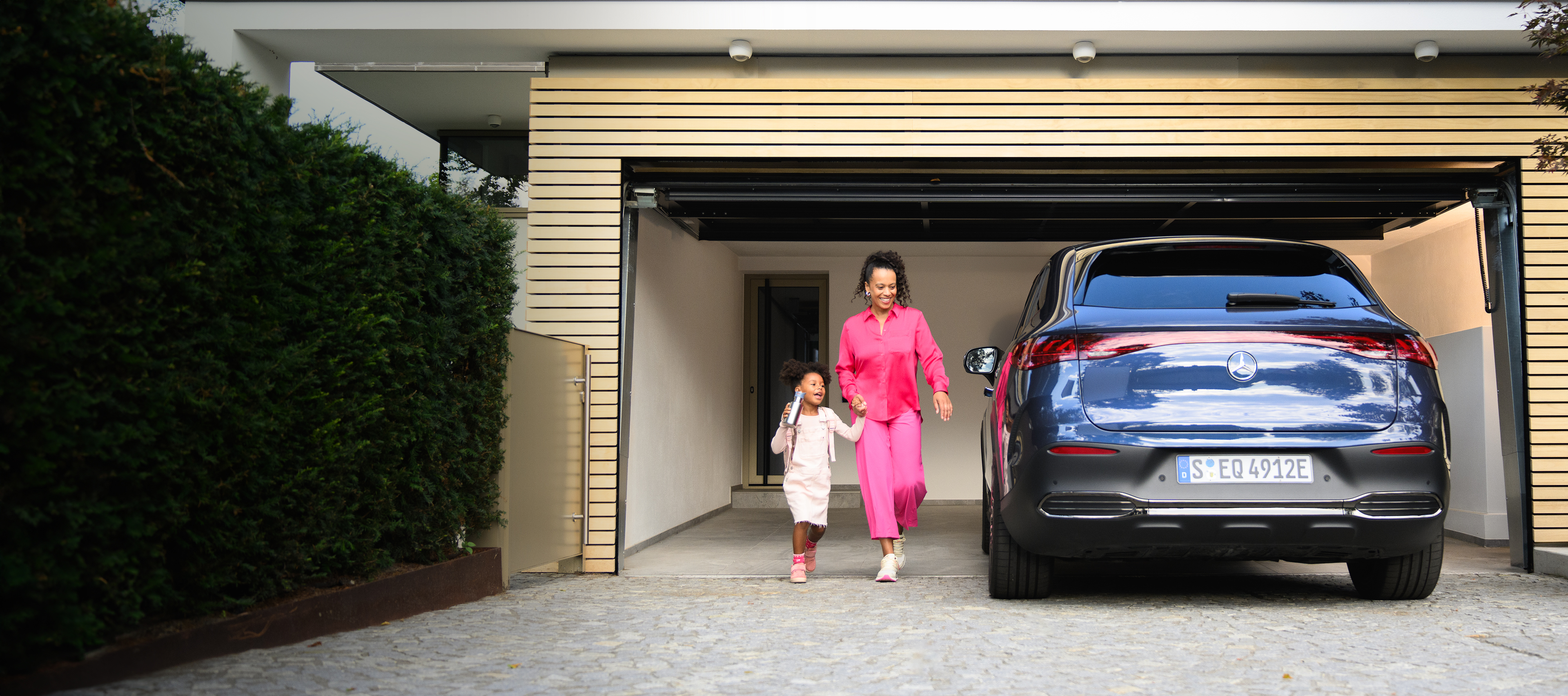 Seguros | Servicios financieros | Mercedes-Benz Una niña y una mujer delante de un EQE SUV de Mercedes-Benz.