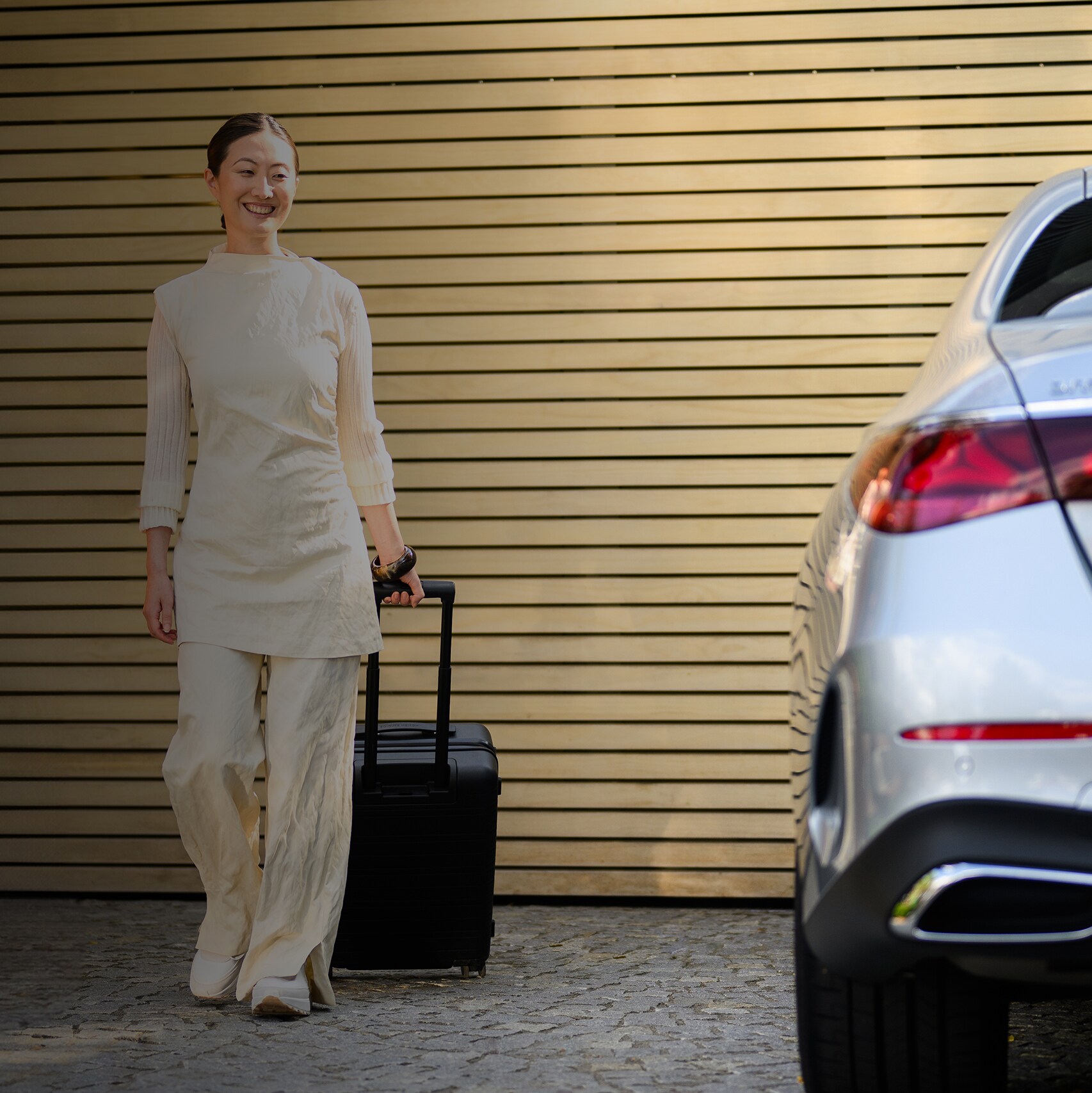 Una mujer caminando con una maleta hacia su Mercedes-Benz